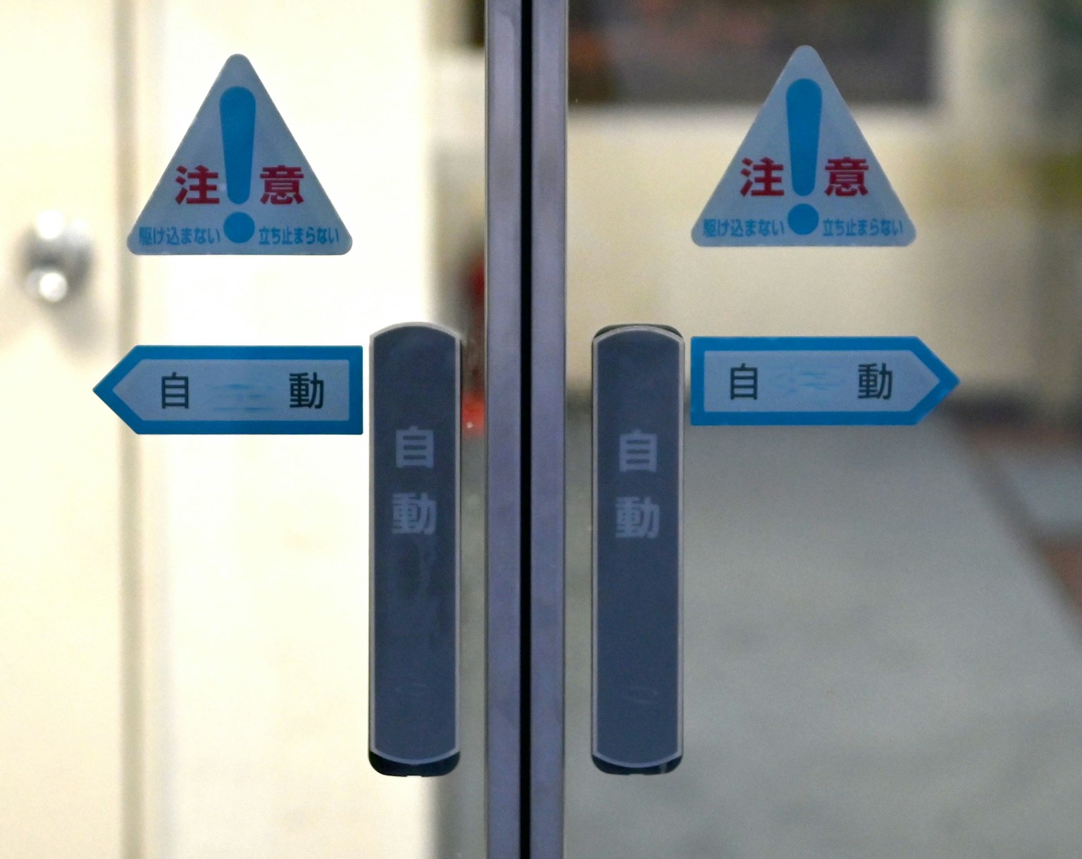 Puerta de vidrio con señales de advertencia de puerta automática e indicadores direccionales