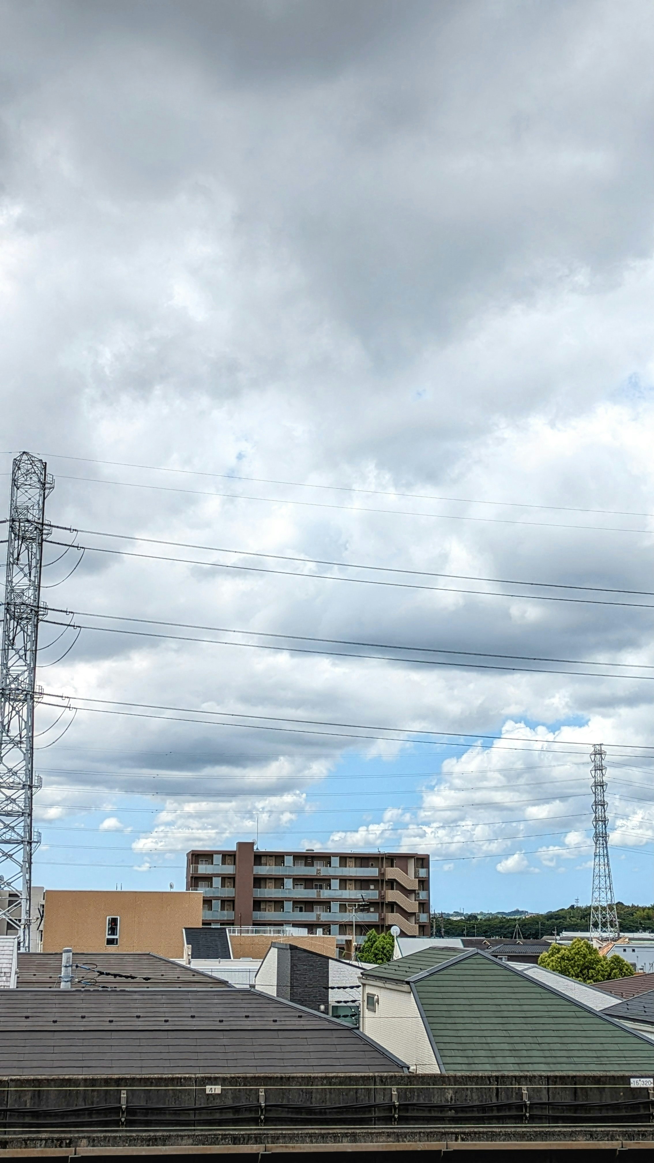 怪しい雲の下の住宅街と電線