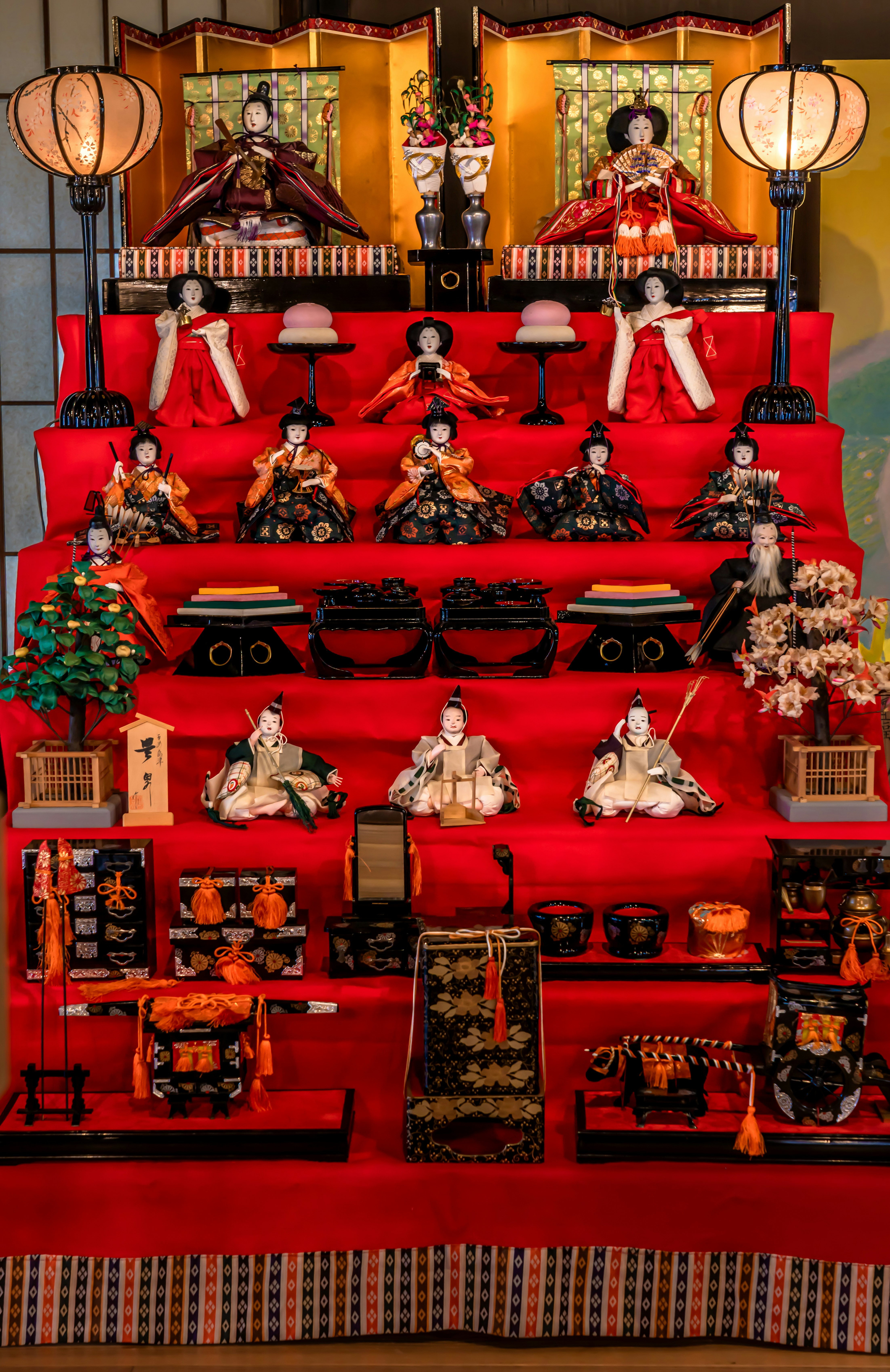 Pajangan boneka Hinamatsuri di atas undakan merah dengan hiasan
