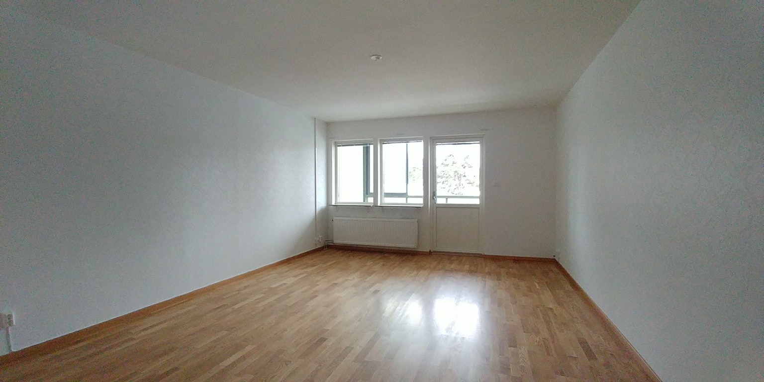 Geräumiger Raum mit weißen Wänden und Holzboden große Fenster, die Tageslicht hereinlassen
