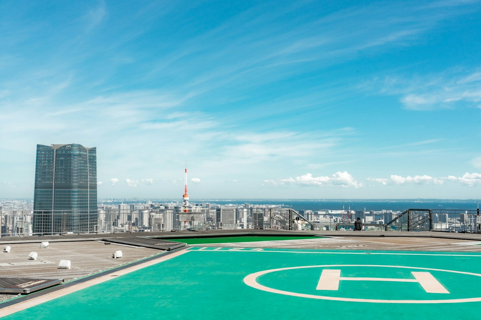 Helipad with a panoramic city view under a blue sky featuring skyscrapers and Tokyo Tower