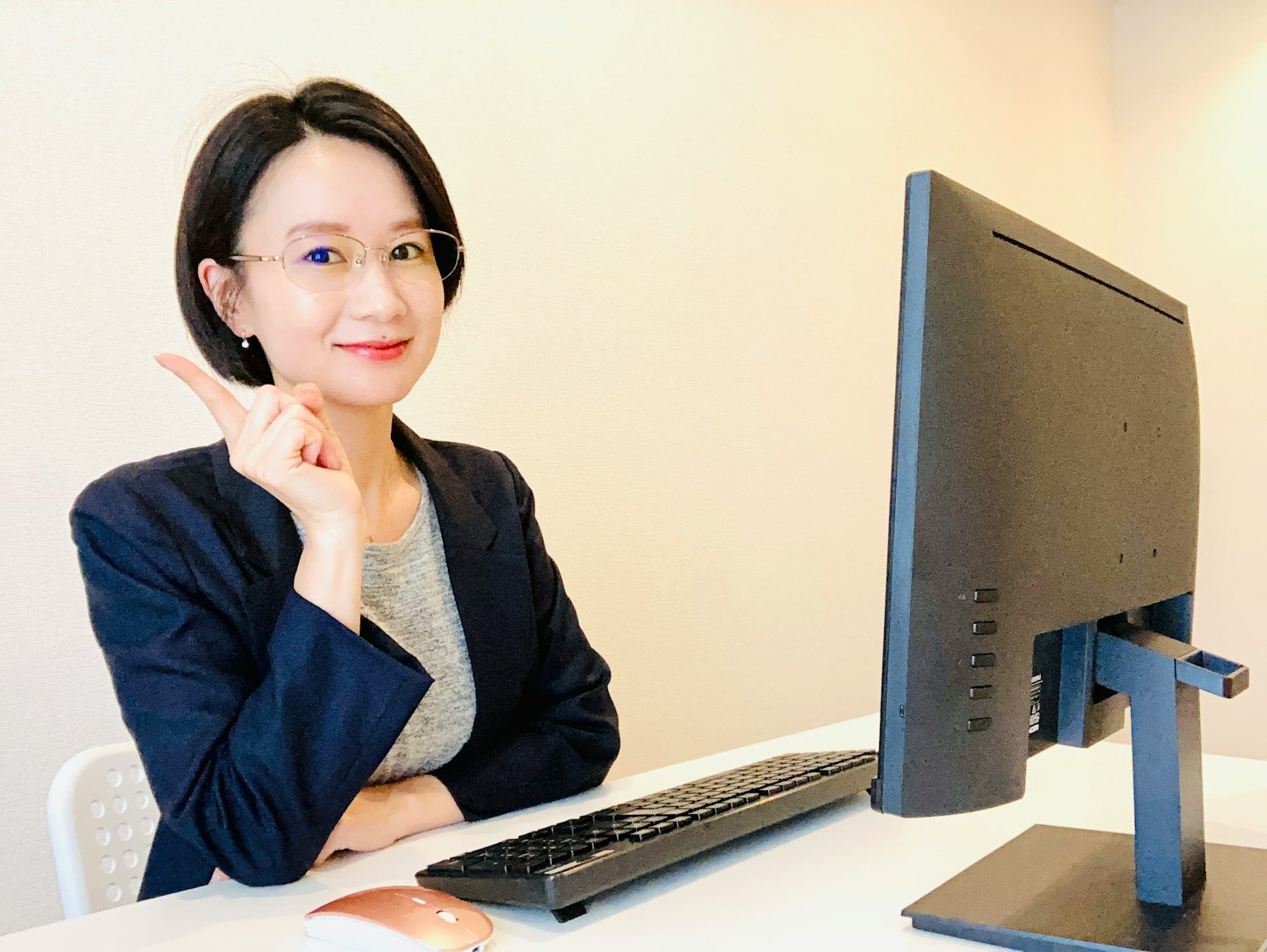 Một người phụ nữ ngồi ở văn phòng trước máy tính, mỉm cười và giơ tay cái lên