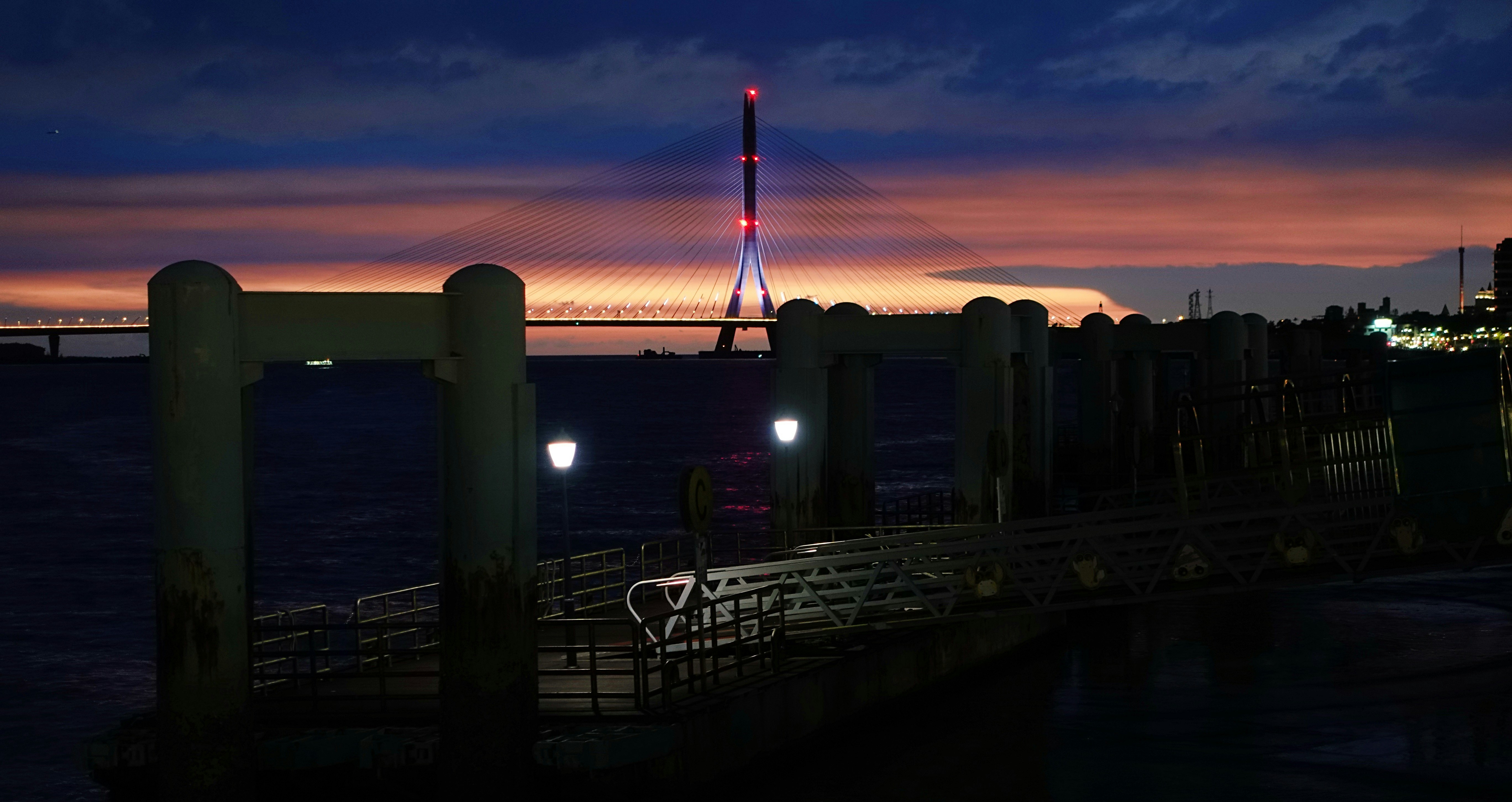 淡水の夕暮れの川沿いのフェンスと夜景、遠くに台北101のシルエット