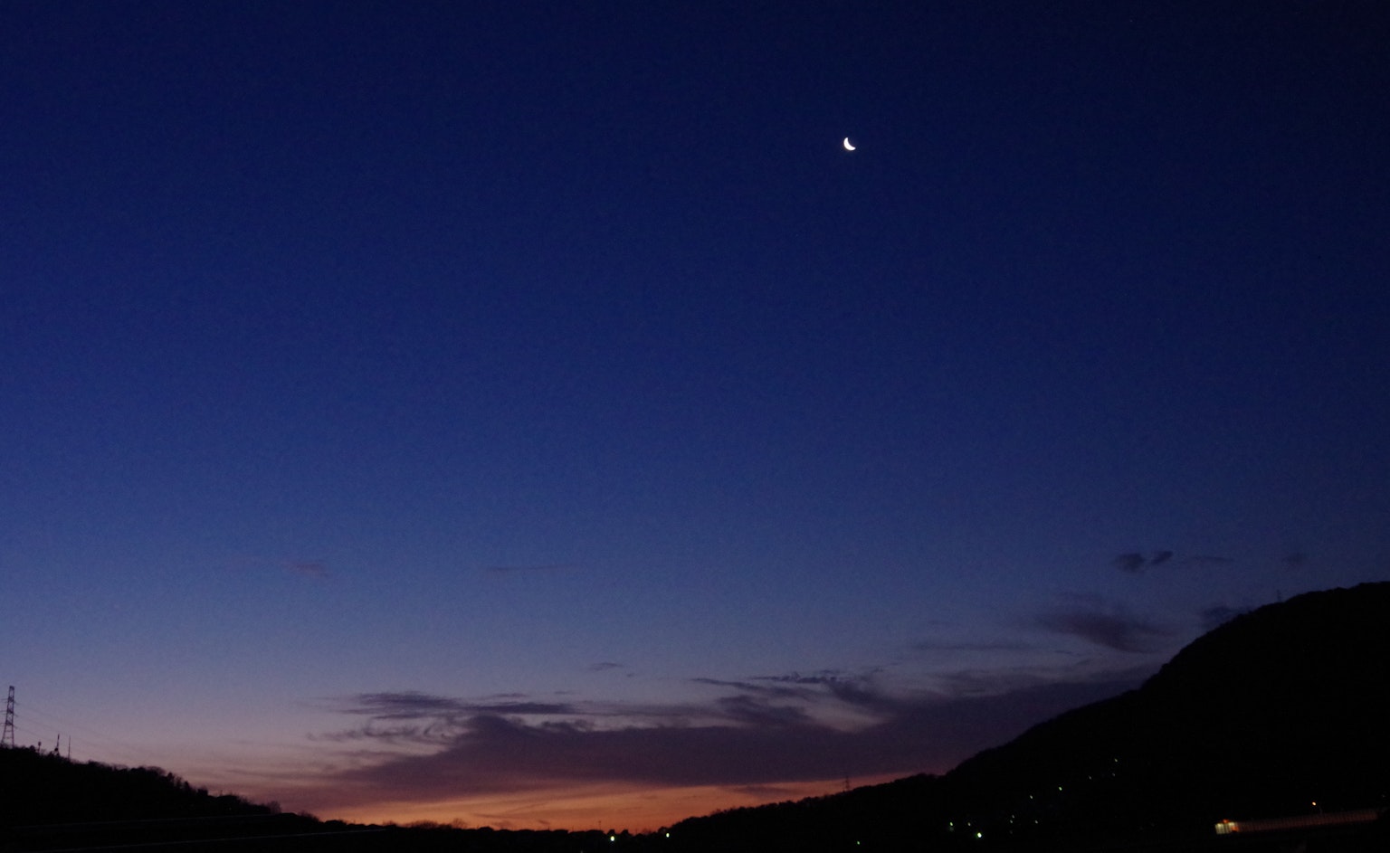 Luna brillante nel cielo al crepuscolo sopra montagne scure