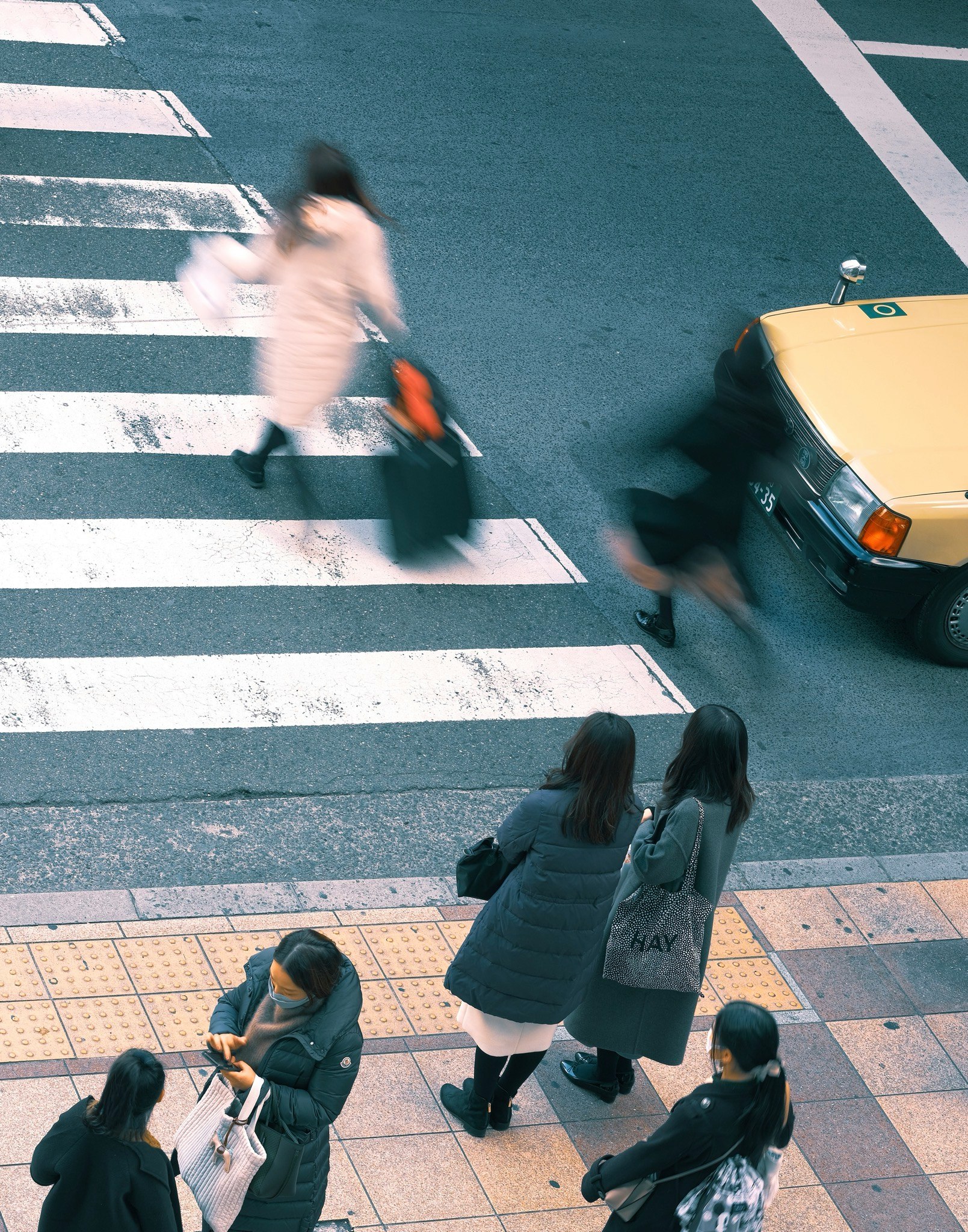 Menschen beim Überqueren eines Zebrastreifens mit Taxi