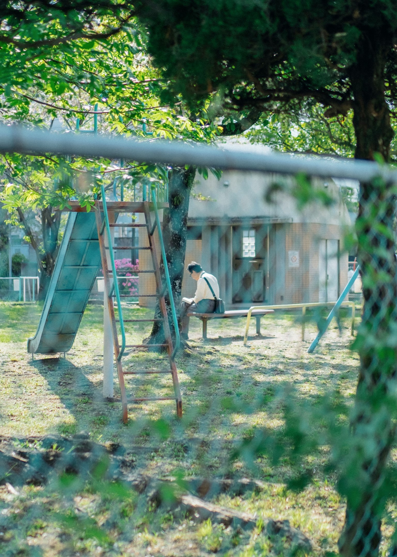 Immagine di un ragazzo seduto su una panchina vicino agli altalene in un parco