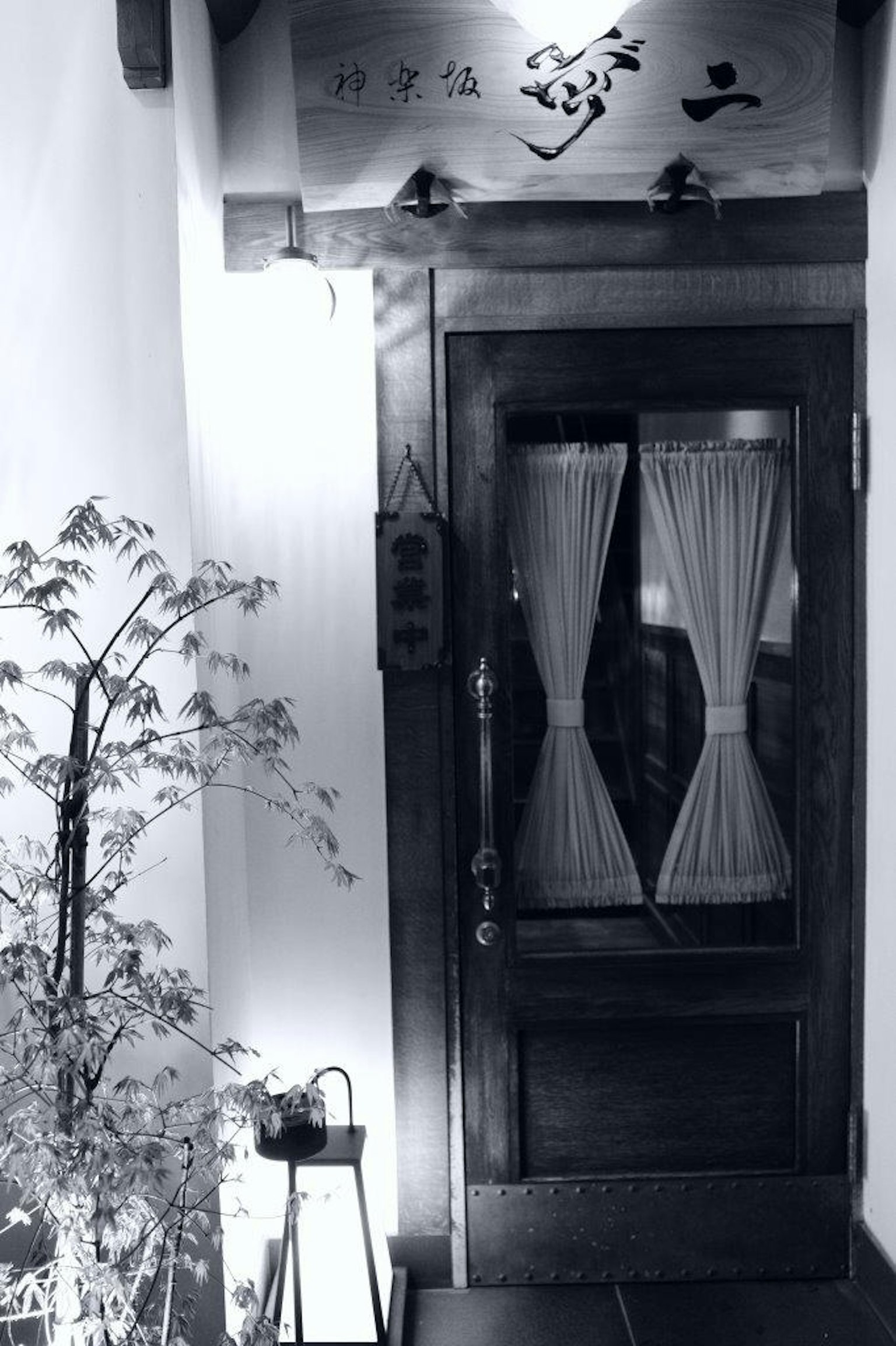 Imagen en blanco y negro de una puerta de madera con cortinas y elementos decorativos