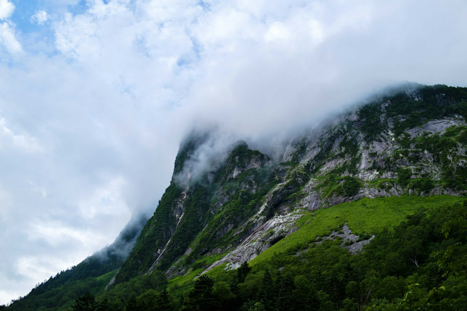 Un paysage de montagne verdoyant enveloppé de nuages