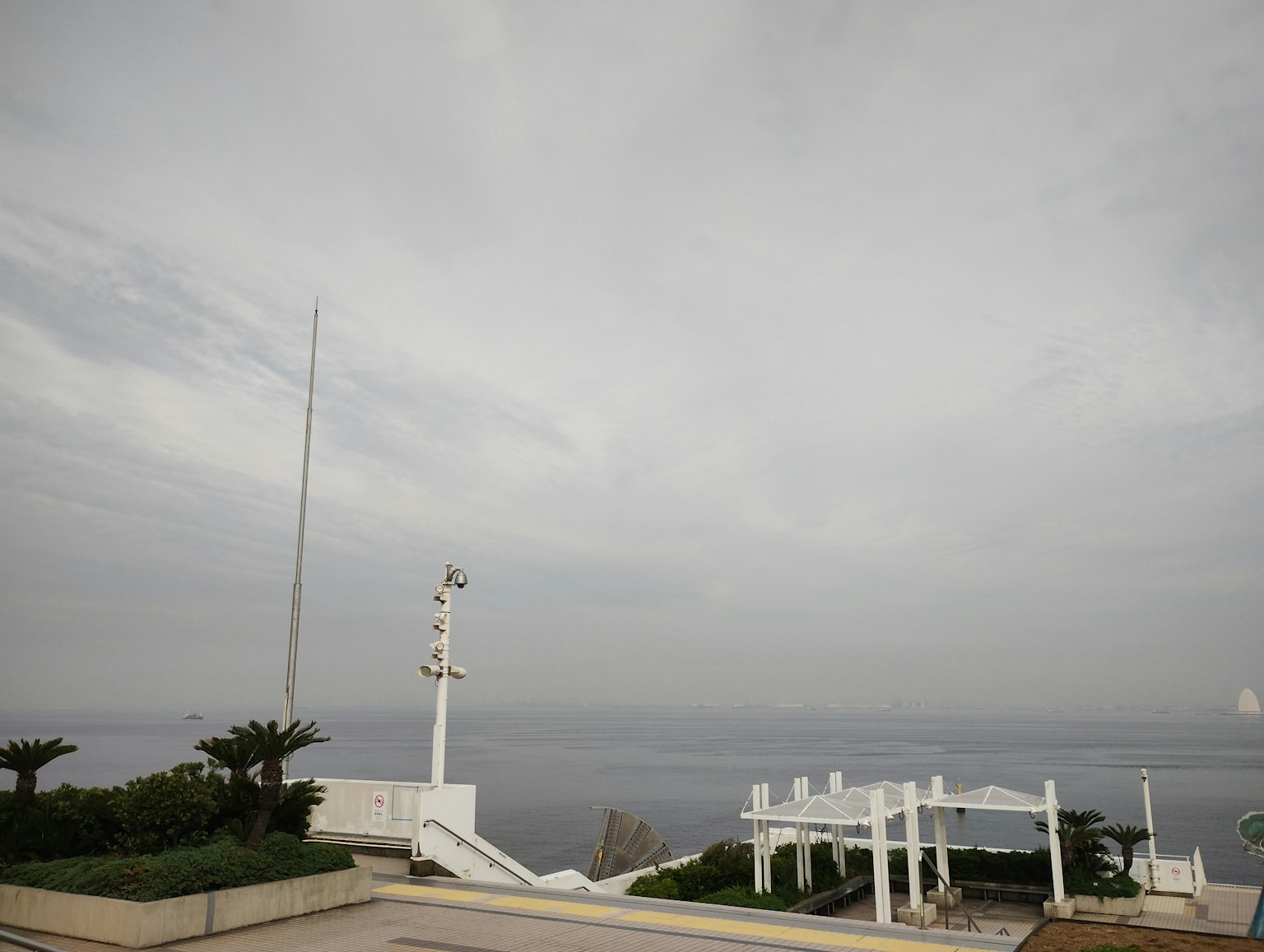 Vista nuvolosa del mare con strutture bianche e un palo della bandiera