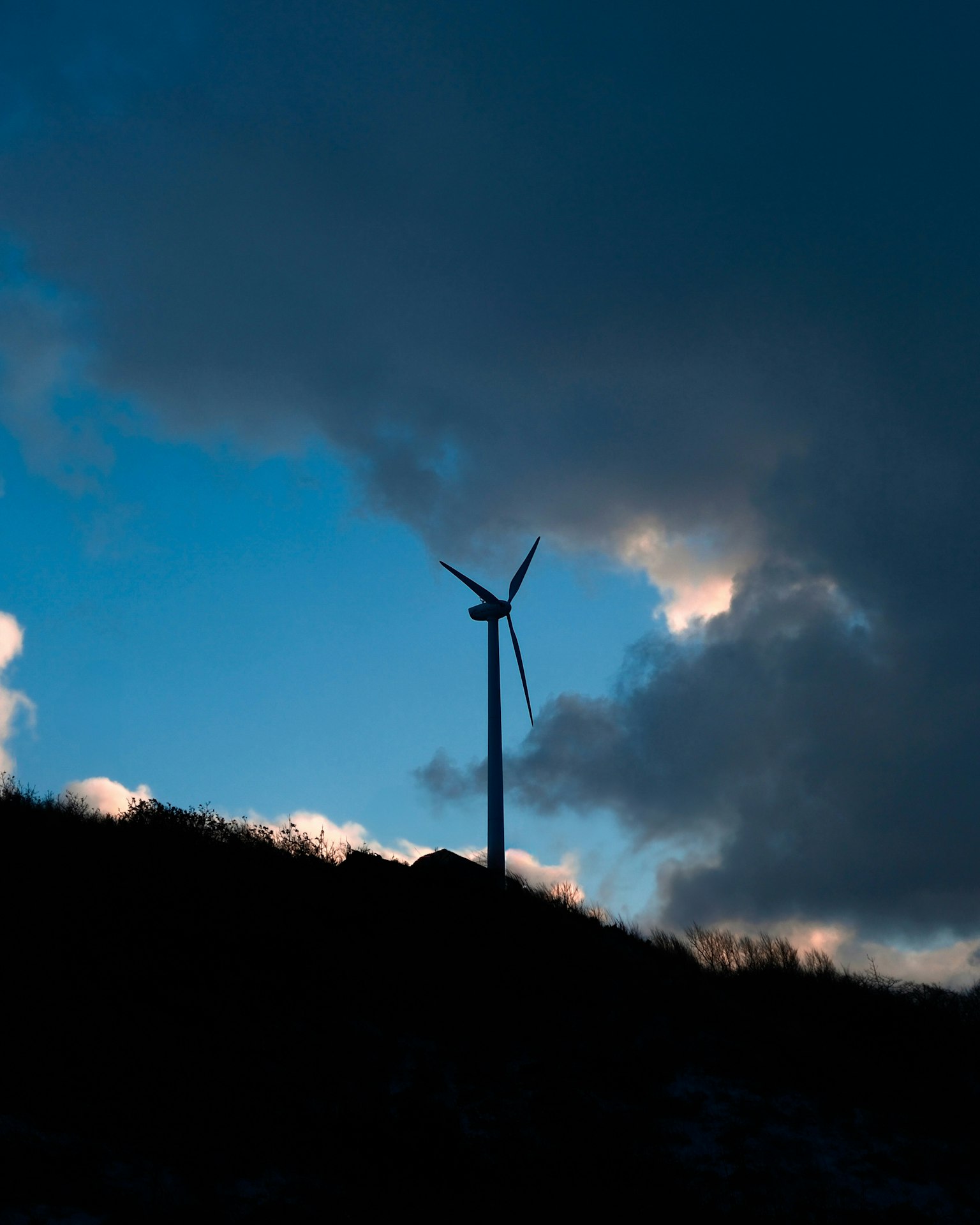 風車がシルエットとして浮かび上がる青い空と雲の風景
