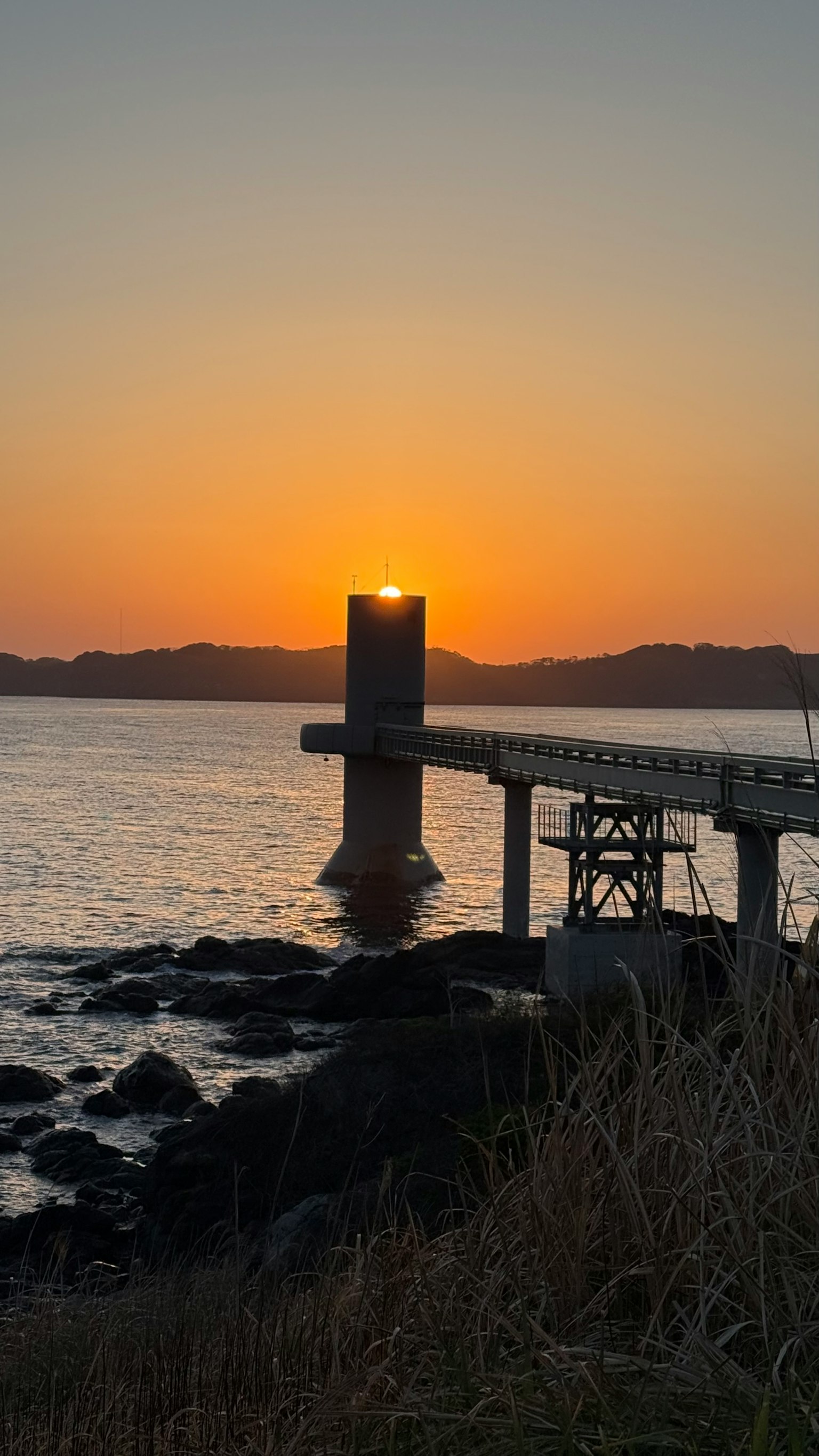 Silhouette di un molo al tramonto con un sole splendente