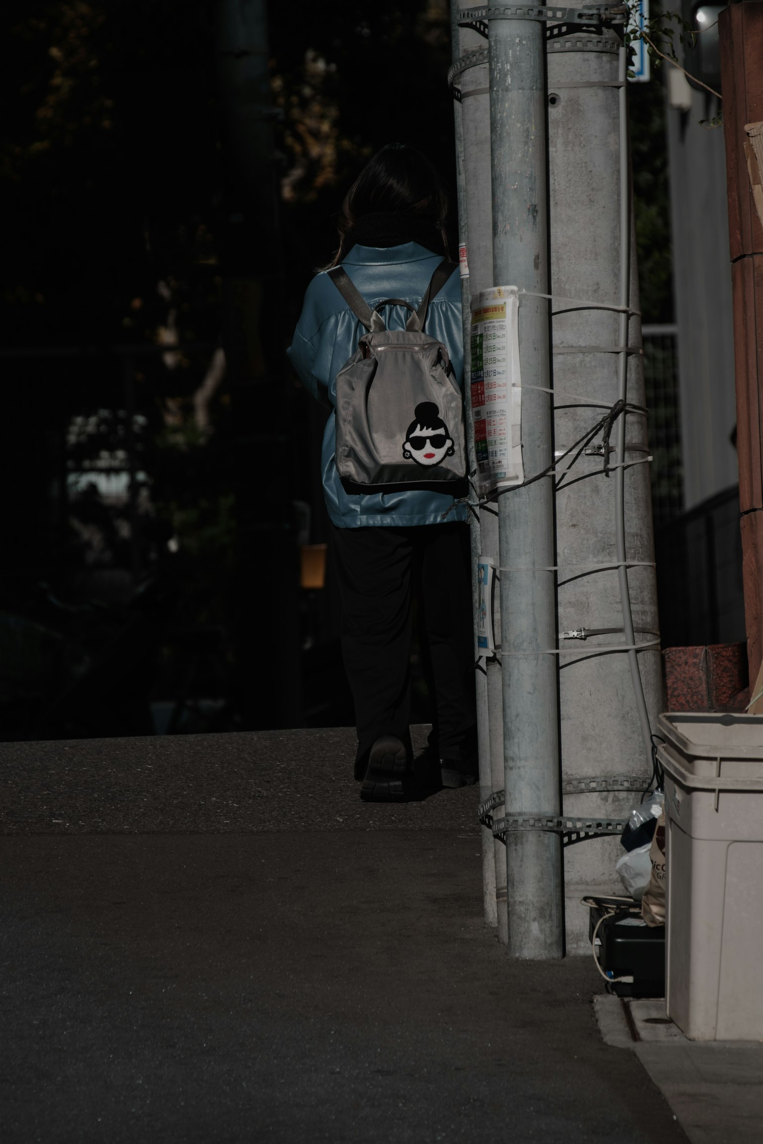 Silhouette of a person walking on a dark street with a backpack