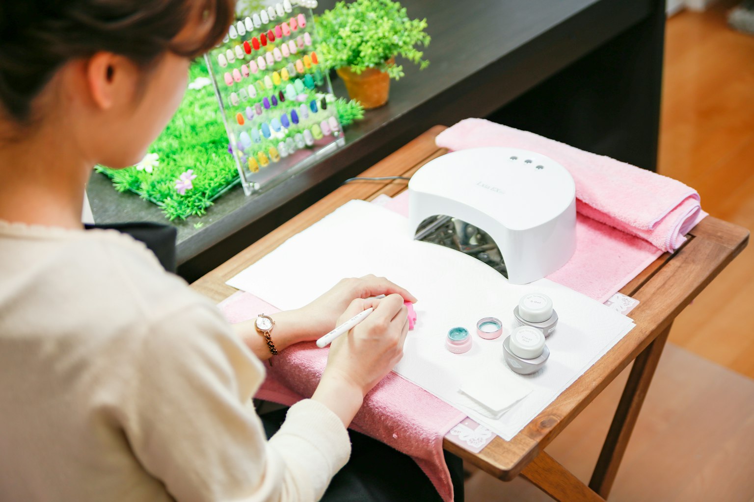 Eine Frau, die Nagelpflege mit einem Nageltrockner und sichtbaren bunten Nagellacken macht