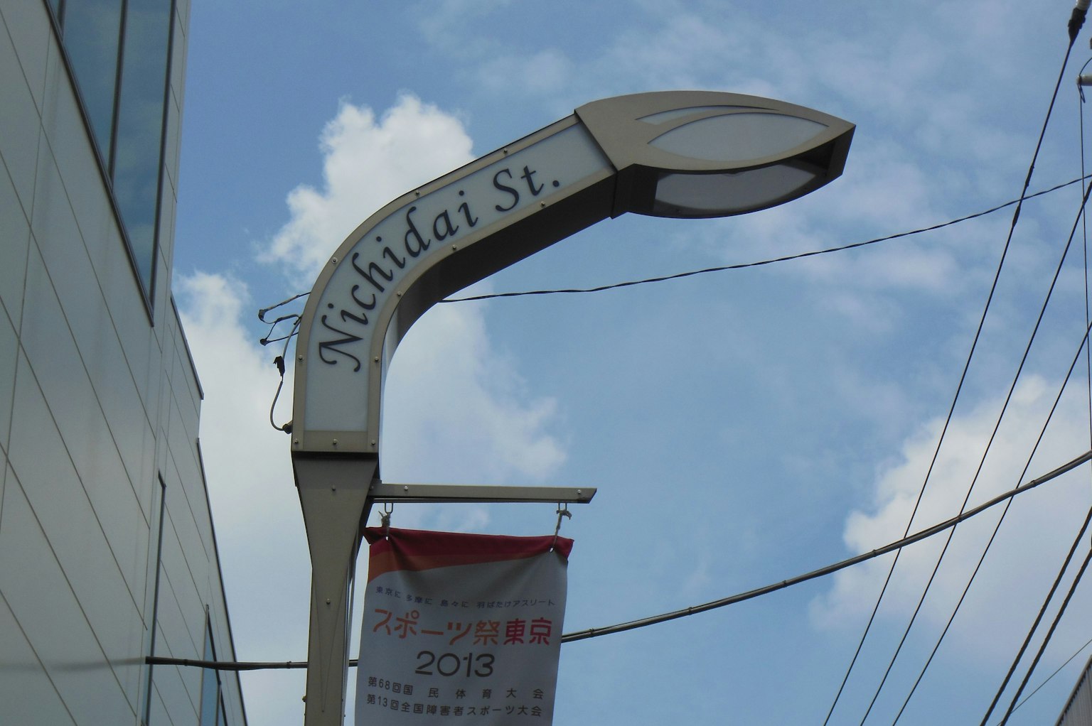 Street sign for Michida St with a lamp under a blue sky