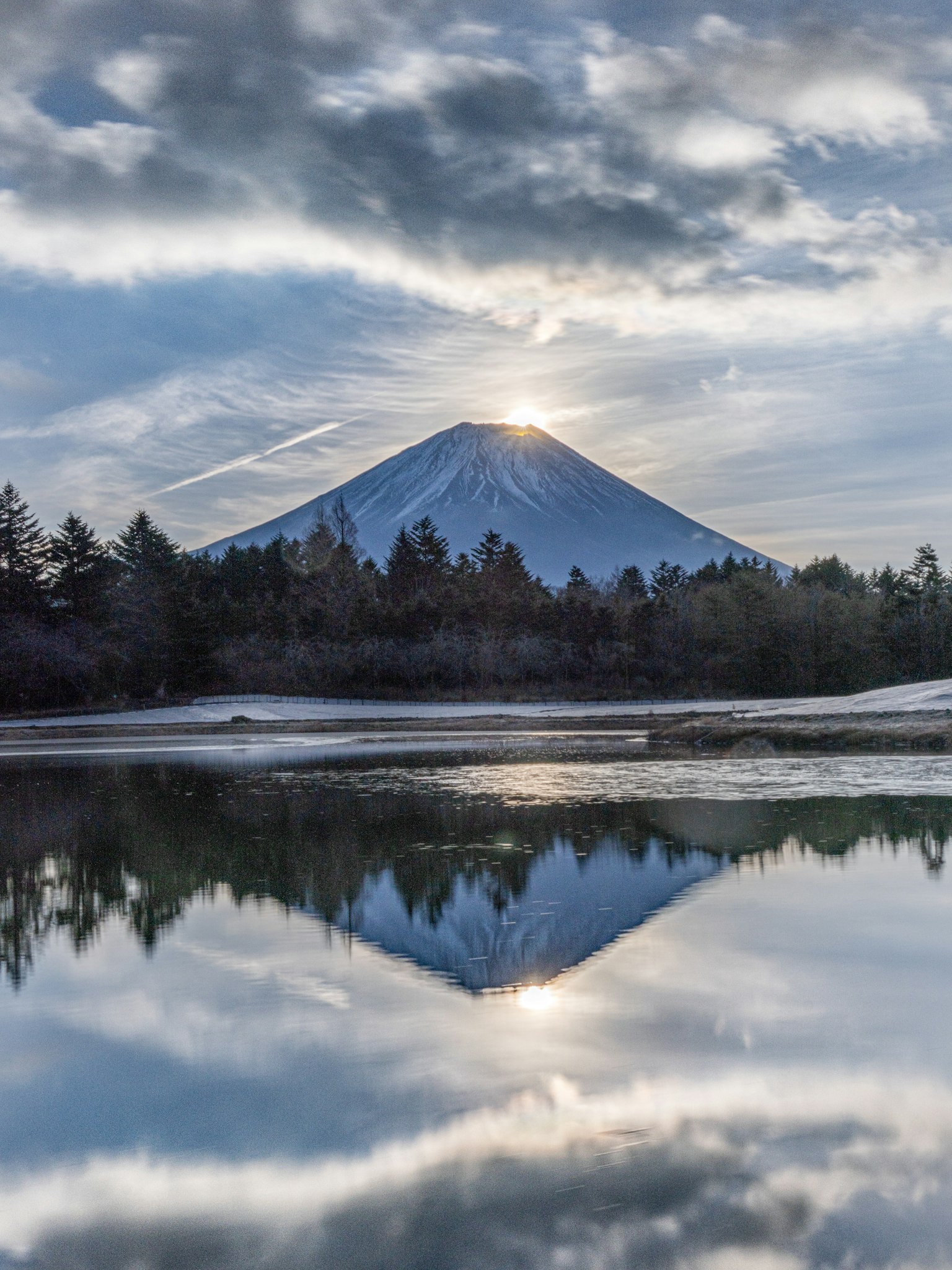 A serene landscape featuring the reflection of Mount Fuji on a calm water surface