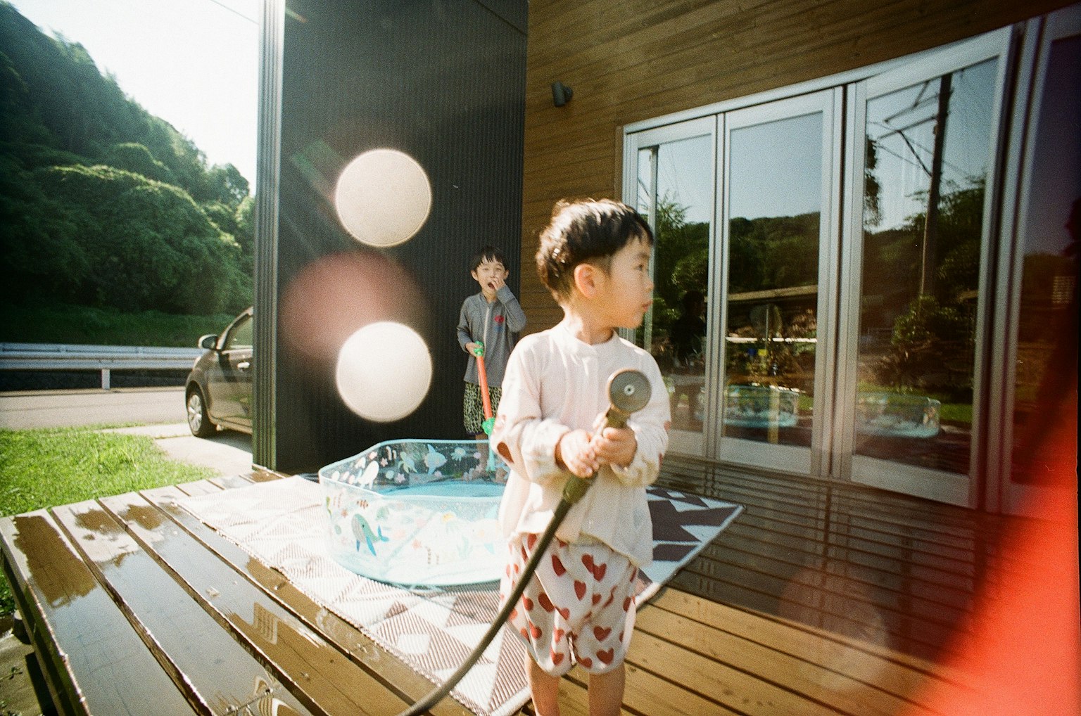 子供がホースを持っている屋外のシーン 大きな白い球体が背景にあり プールが近くにある