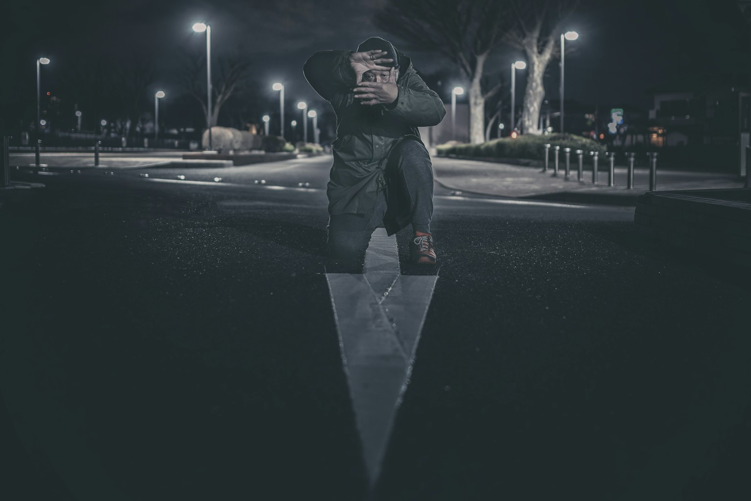 Un hombre posando sobre una estructura triangular en un entorno urbano nocturno