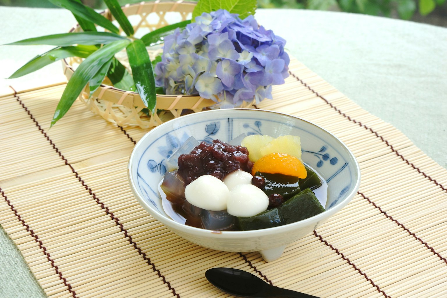 Tazón de postre japonés con bolas de mochi y pasta de frijoles rojos dulces con flores de hortensia al fondo
