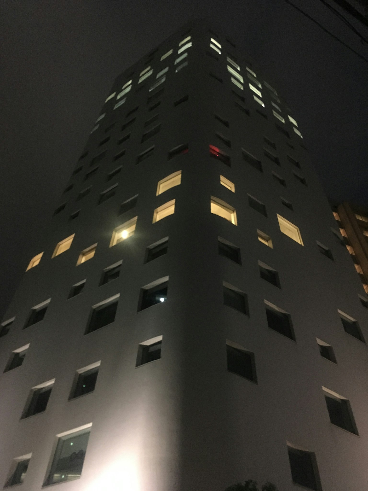 Modernes Hochhaus, das nachts beleuchtet ist mit markanten leuchtenden Fenstern