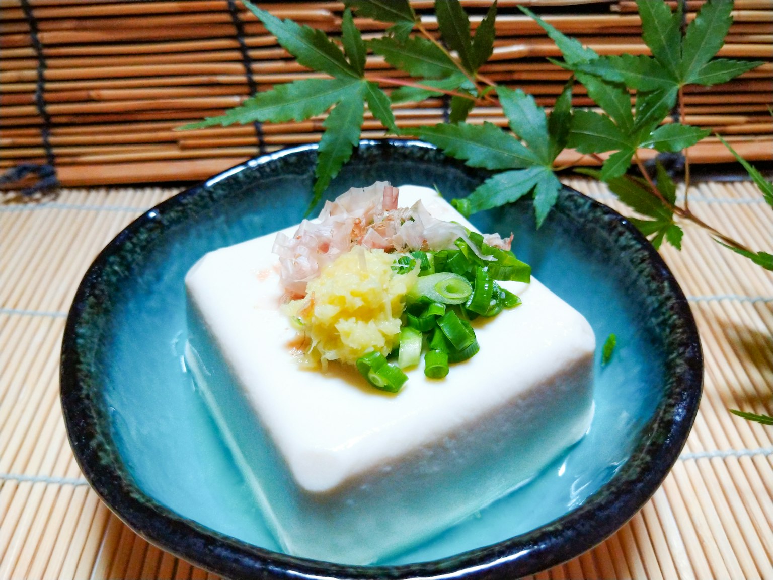 蓝色碗中的豆腐，上面放有生姜、葱和鲣鱼片