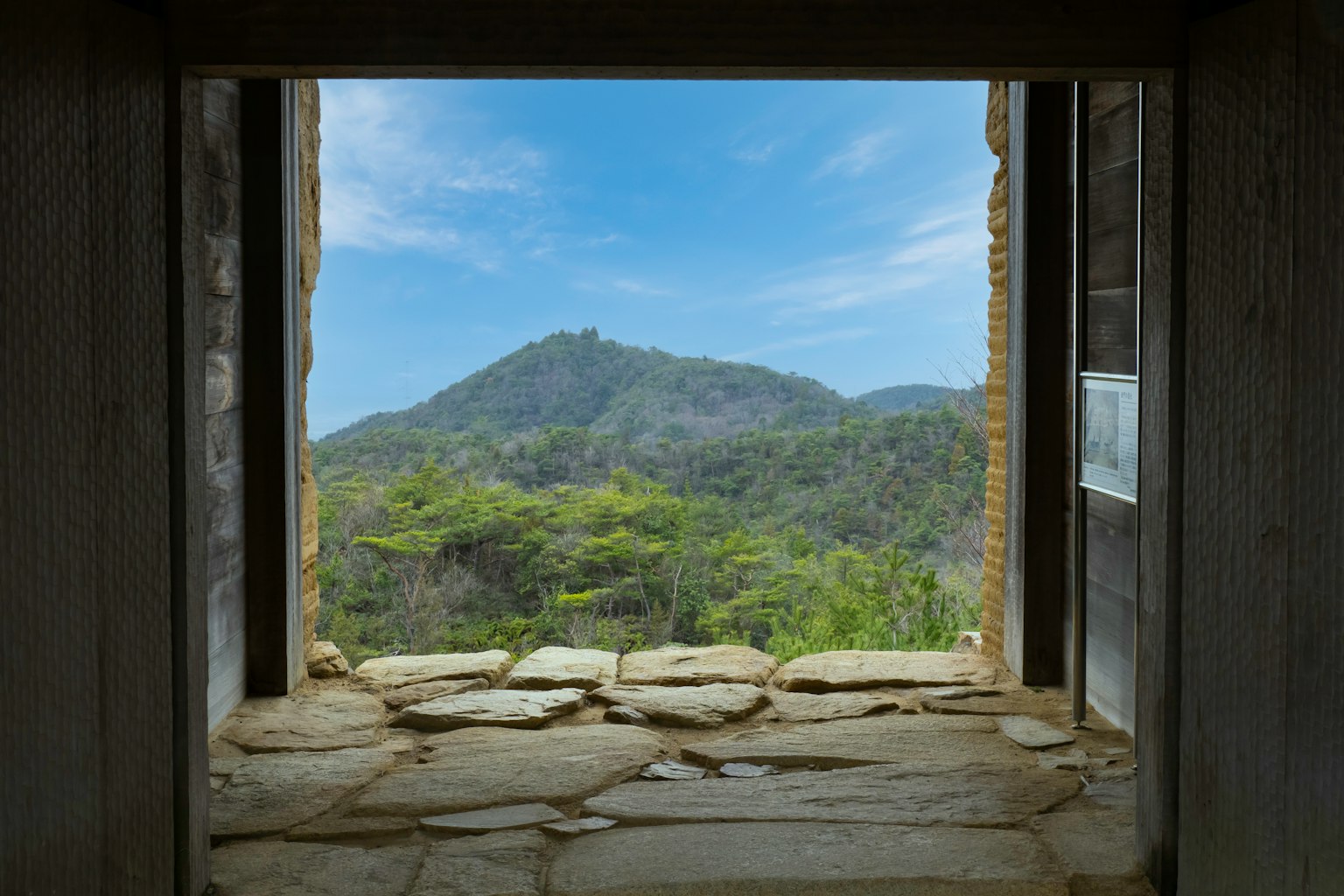 View from a window showcasing mountains and lush greenery