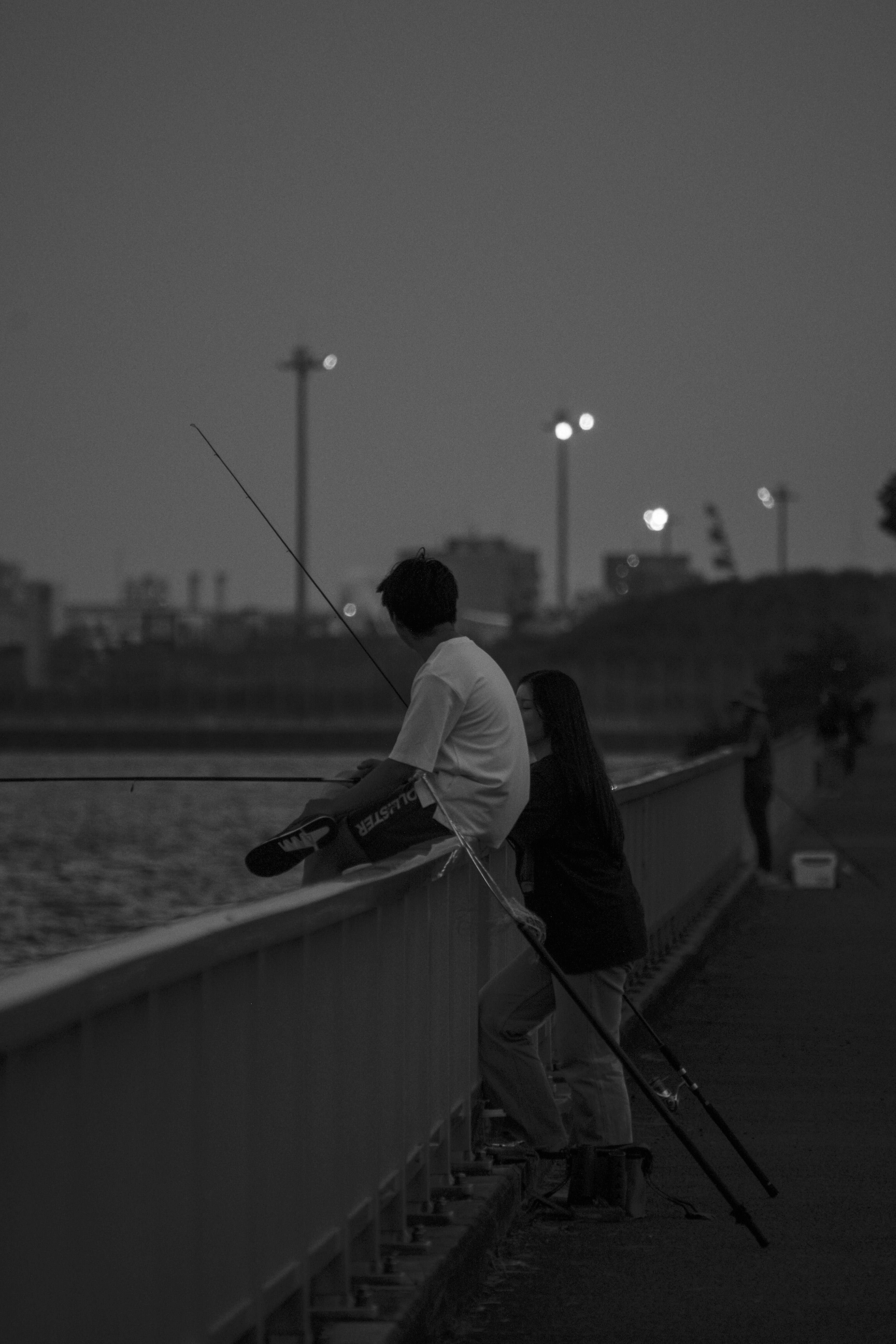 堤防の上で釣りをする人の後ろ姿
