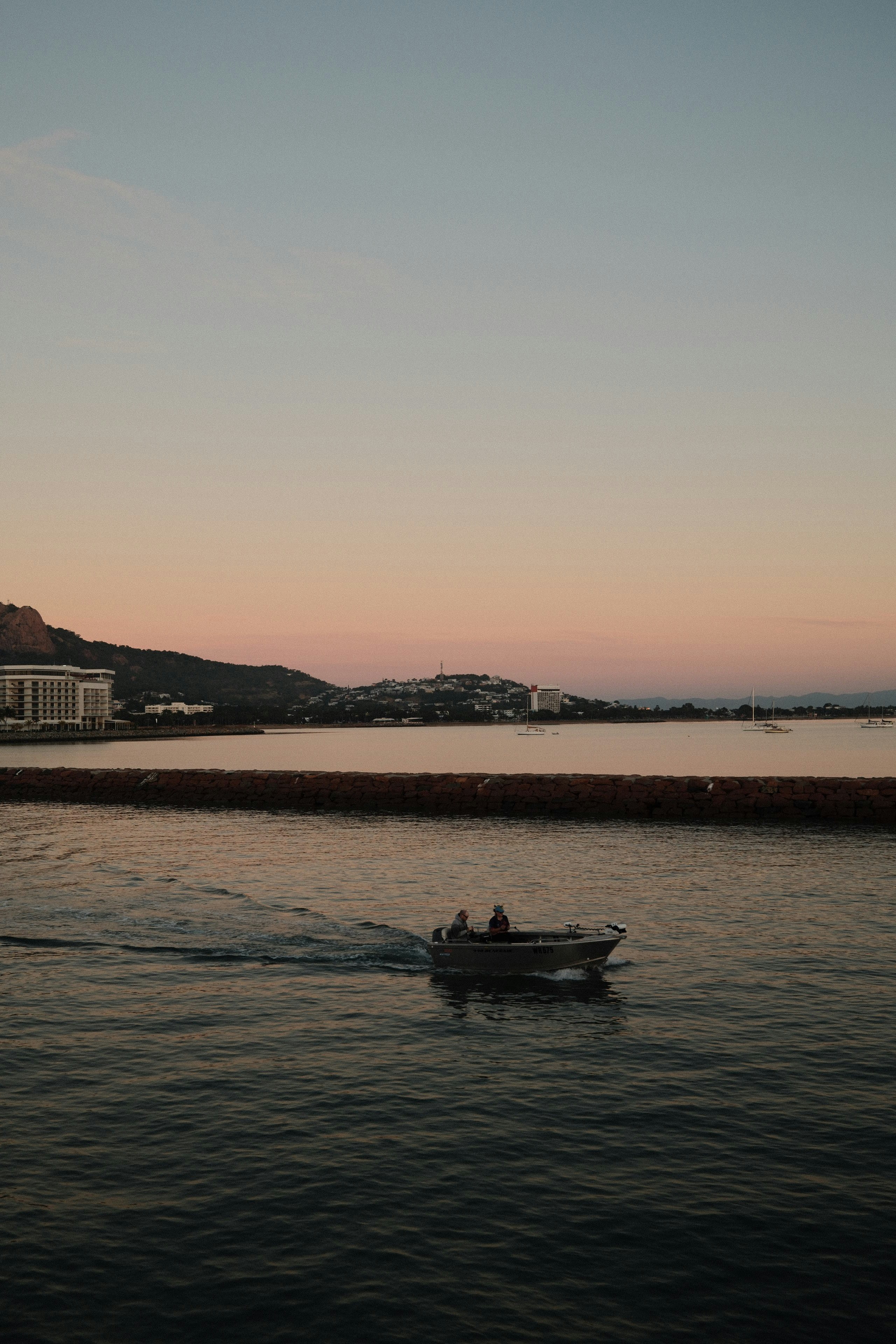 夕暮れの海辺を進む小型ボートのある風景