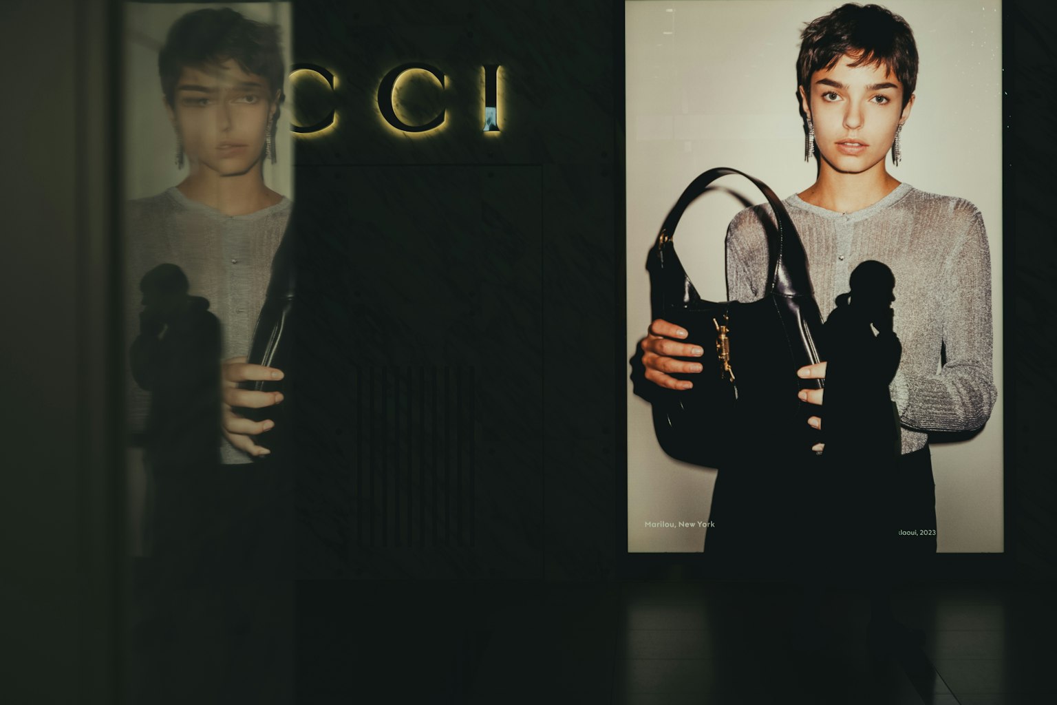 Một người mẫu cầm túi xách trong cửa hàng GUCCI có logo rõ ràng