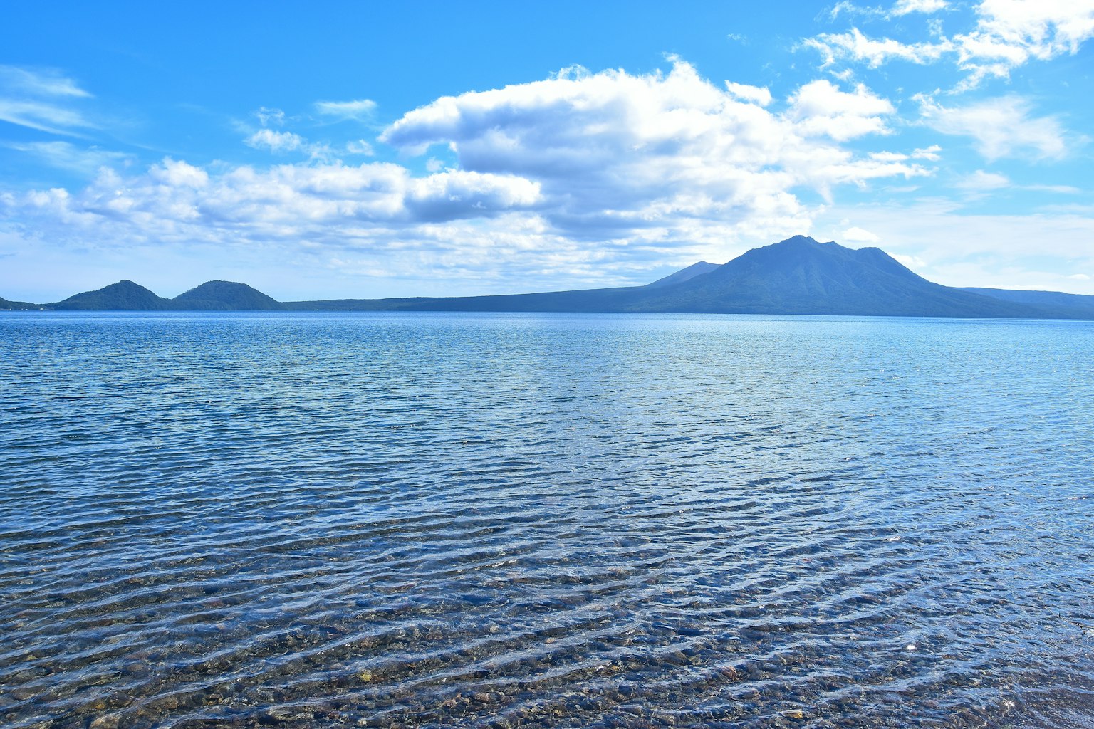 Vista panoramica di un lago blu con montagne lontane e acqua increspata