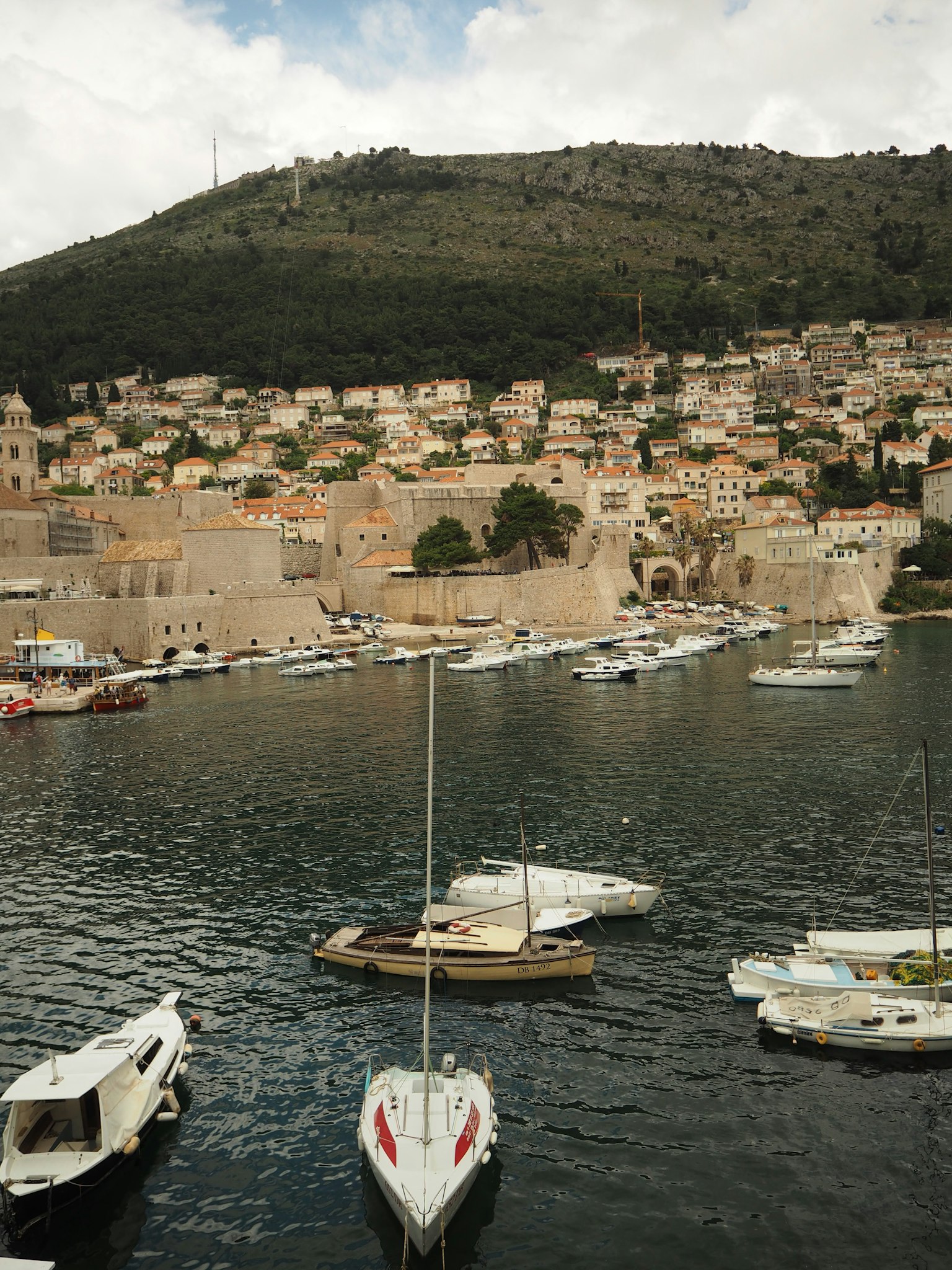 Piccole barche ormeggiate nel pittoresco porto di Dubrovnik con uno sfondo montuoso