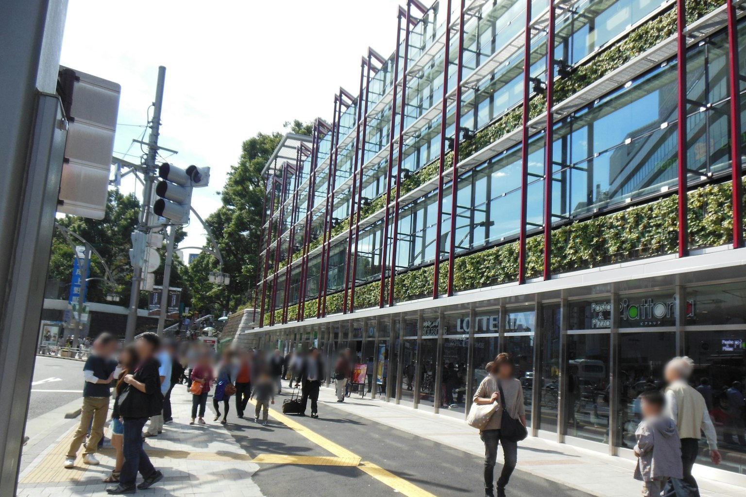 Bâtiment en verre moderne avec murs végétaux dans une scène de rue animée