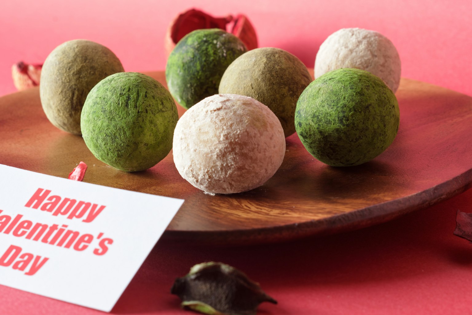 Bolas coloridas dispuestas en un plato de madera con una tarjeta Feliz Día de San Valentín