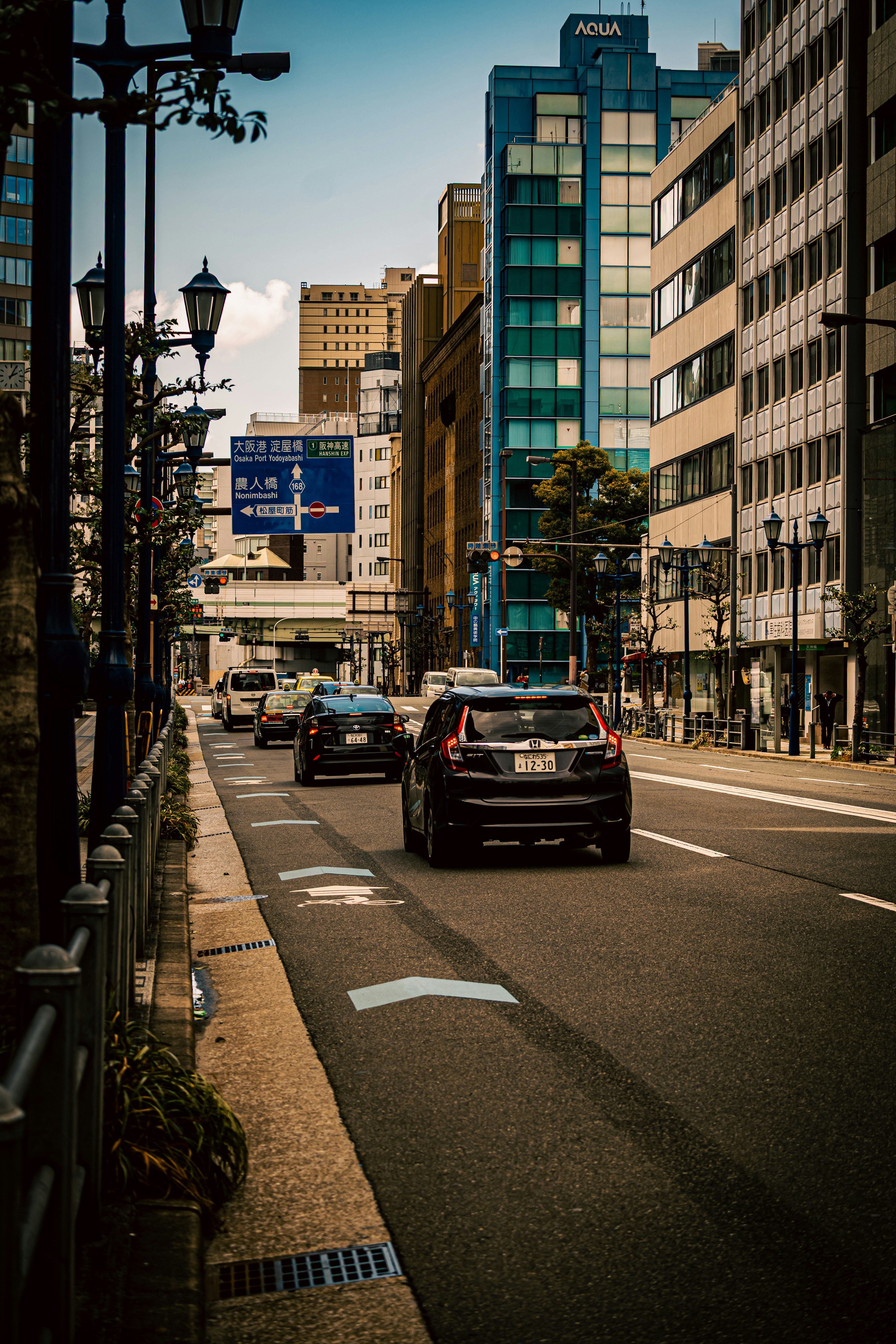 高層ビルに囲まれた街路を走る車のある都市風景