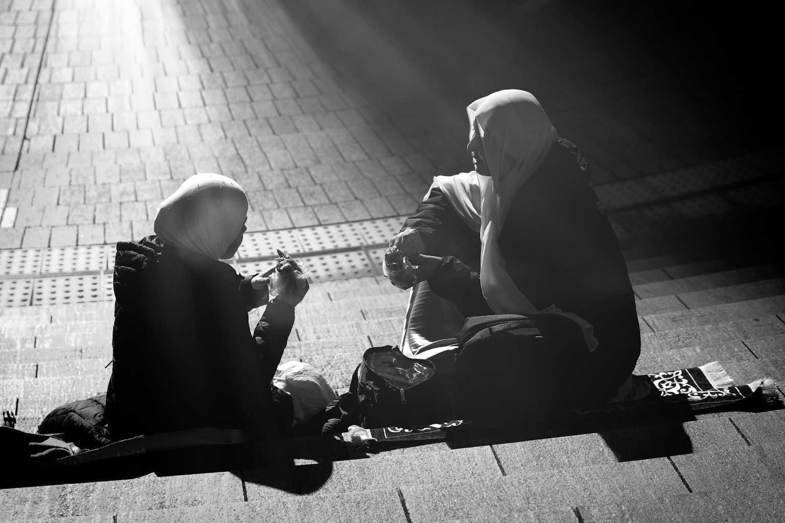Deux femmes assises tranquillement dans une image monochrome entourée de lumière douce