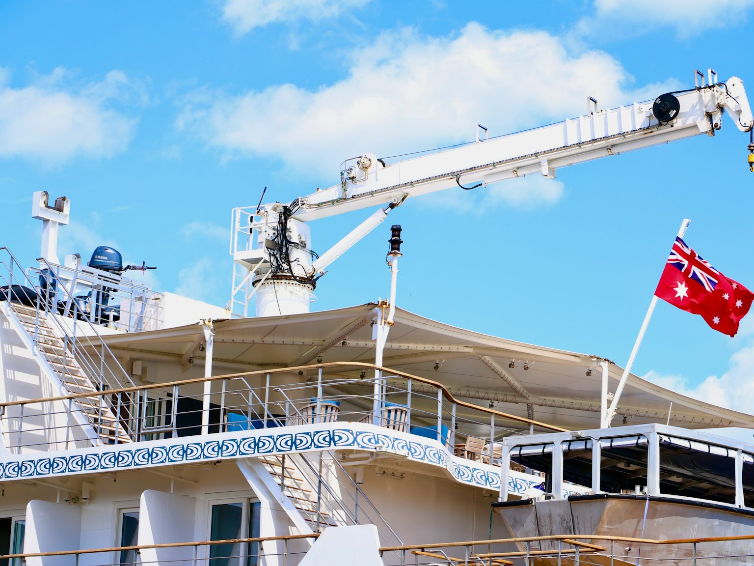 Una cubierta de barco con una grúa y una bandera contra un cielo azul