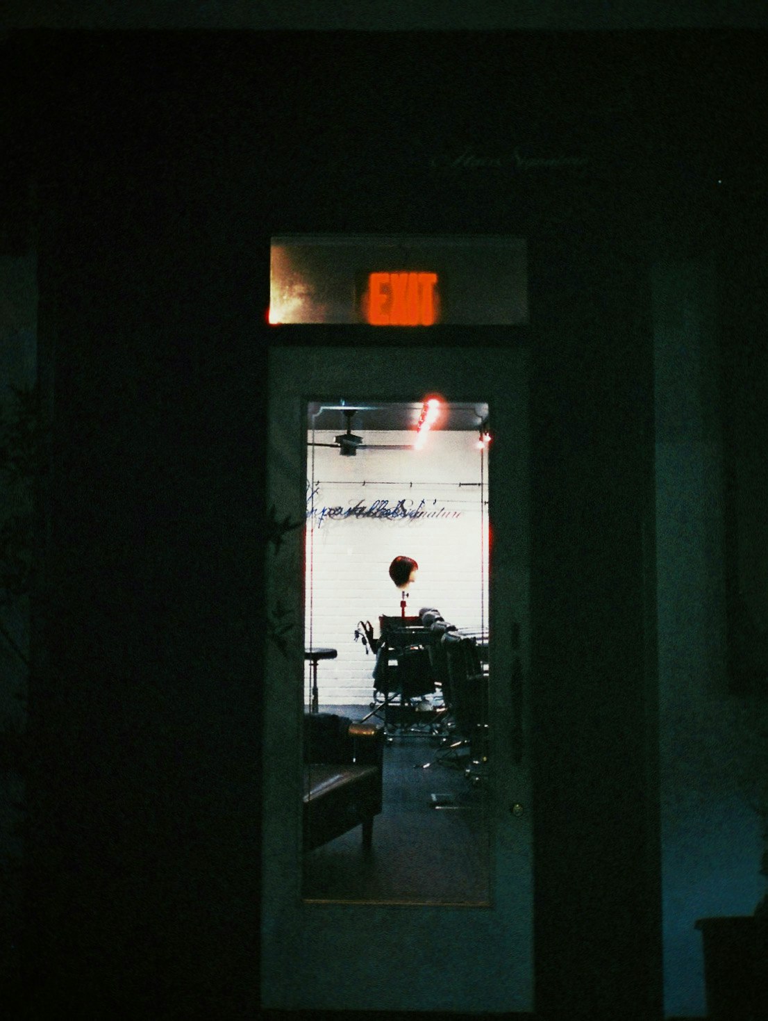 Vue sombre d’une porte intérieure sur du matériel de tournage et une enseigne néon rouge