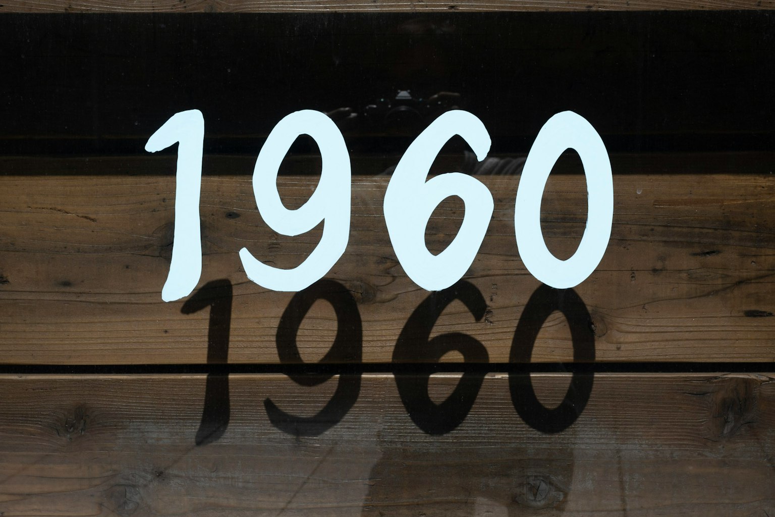 Weiße Zahlen 1960 auf einer Holzoberfläche mit schwarzem Hintergrund
