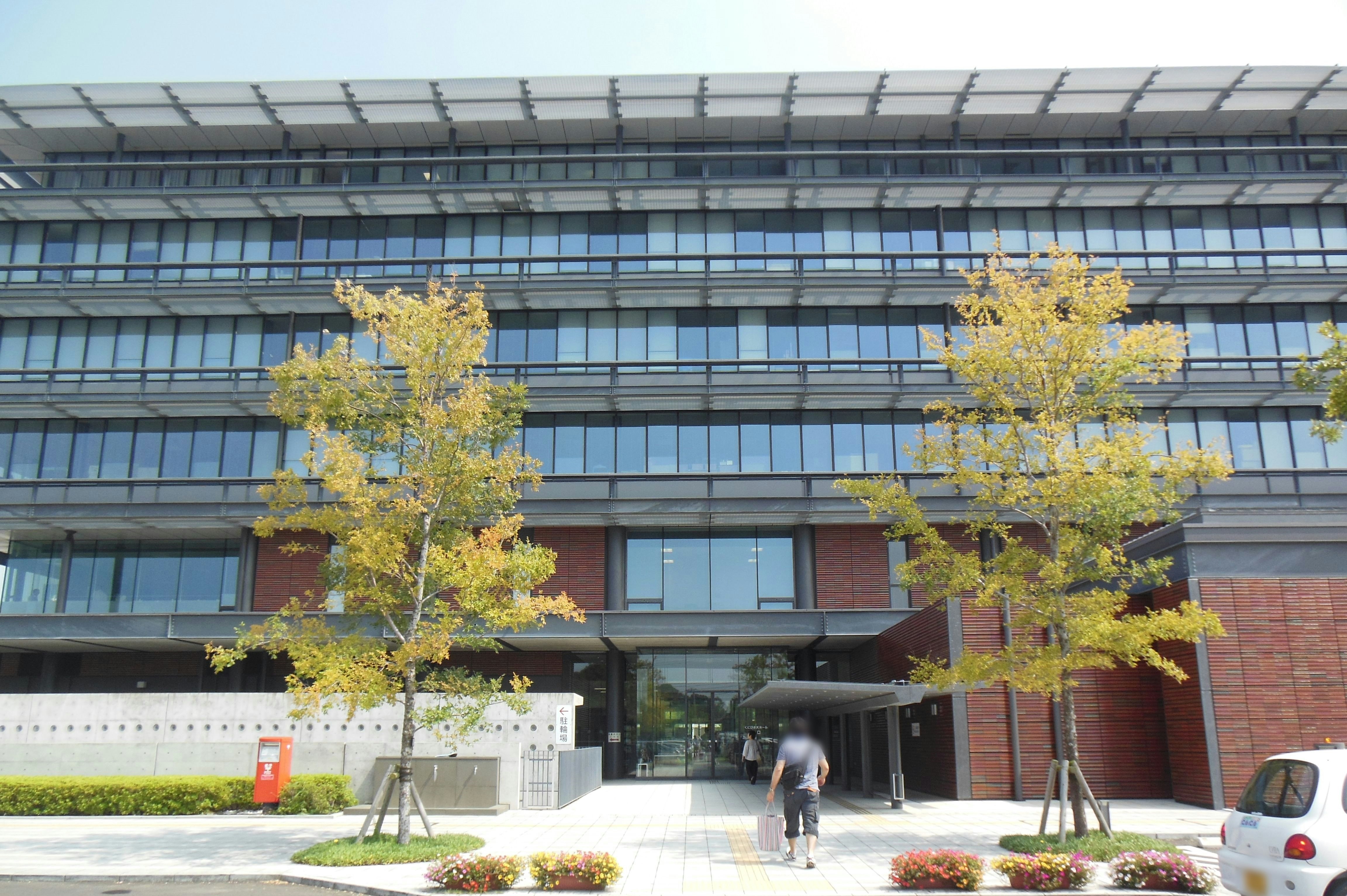 glass office building entrance with trees and walkway