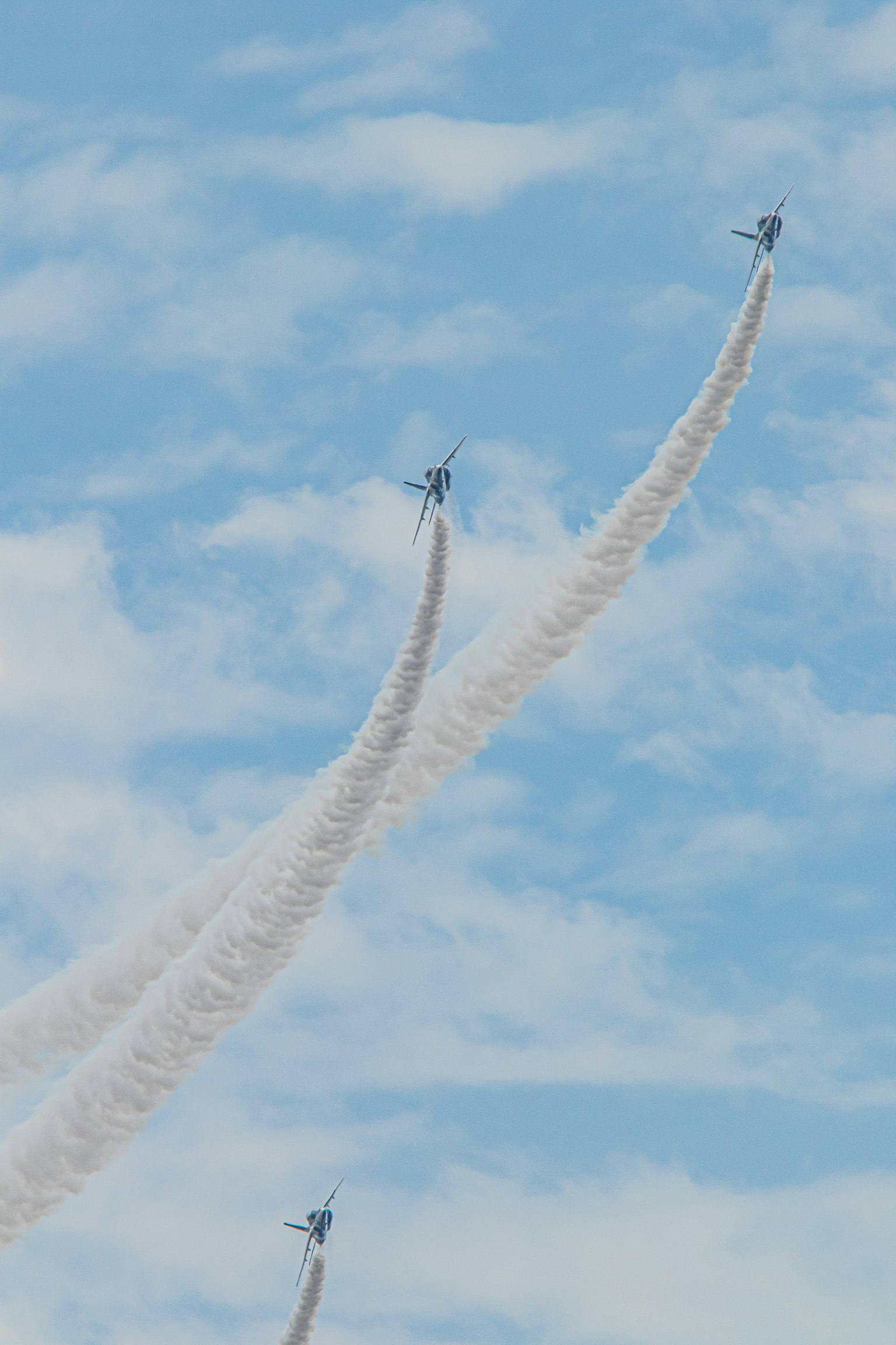 Pesawat terbang di langit dengan jejak asap putih di latar belakang biru