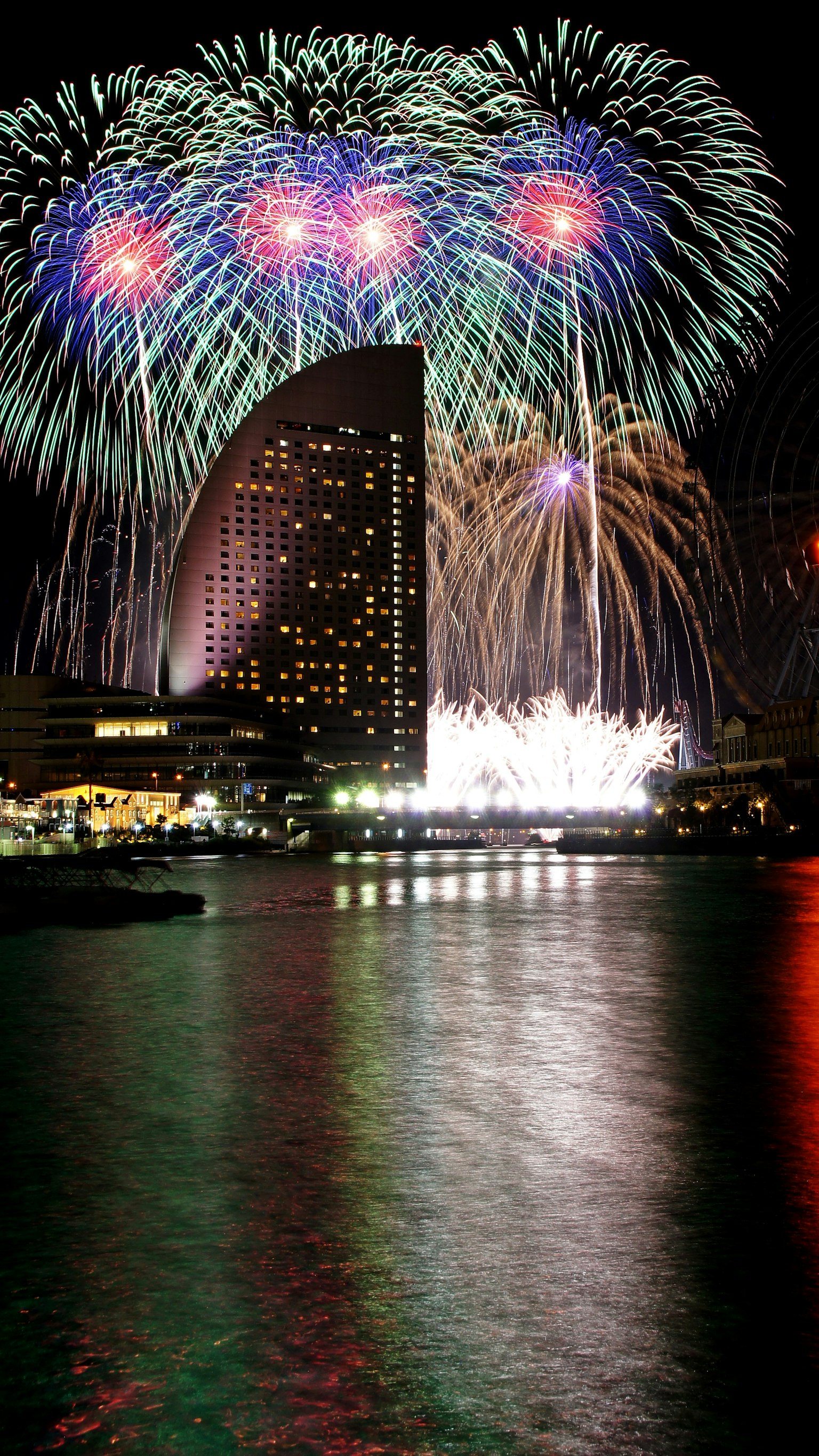 Fuochi d'artificio colorati che esplodono nel cielo notturno riflettendosi sull'acqua