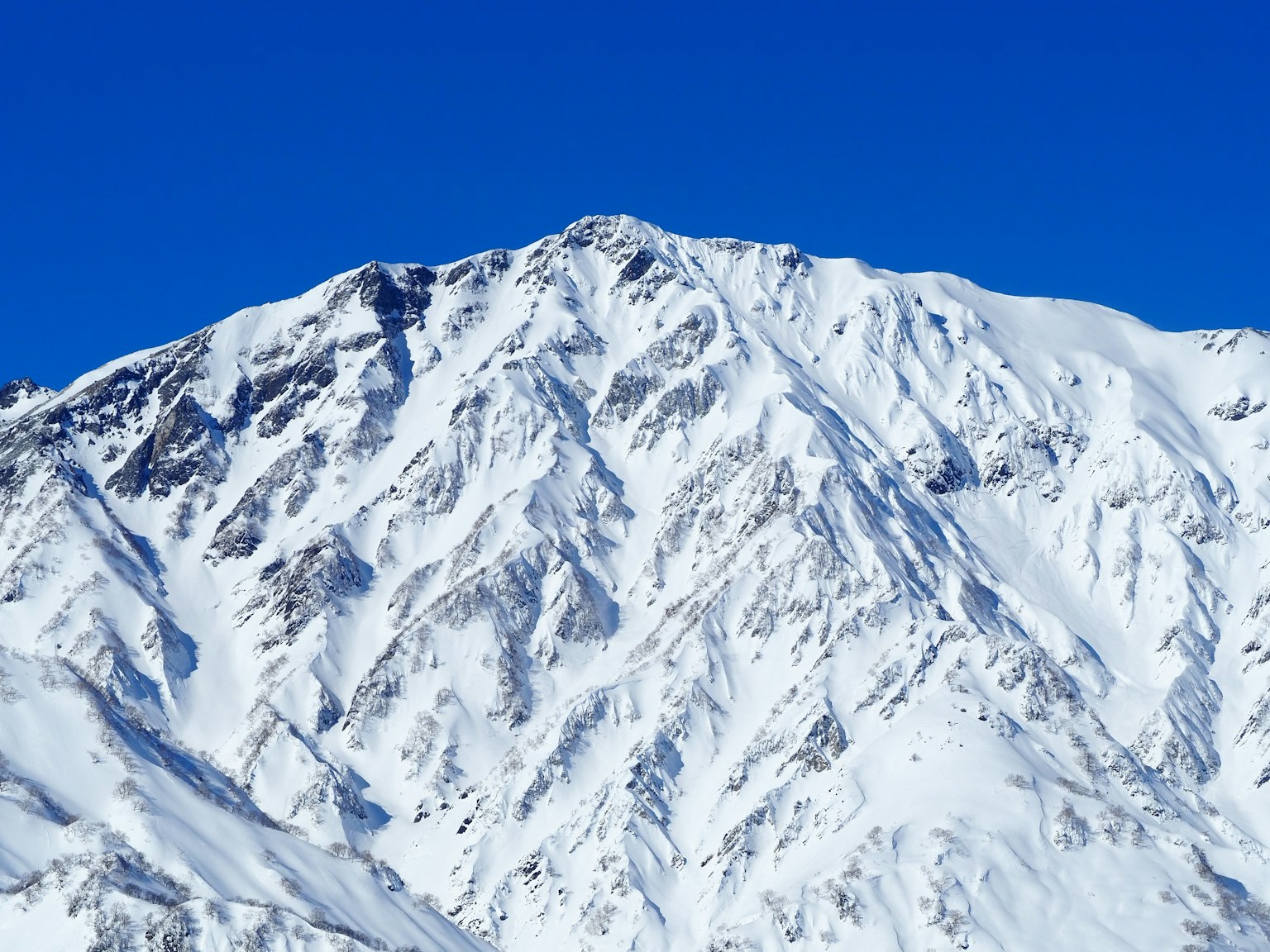 Schneebedeckte Berglandschaft vor blauem Himmel