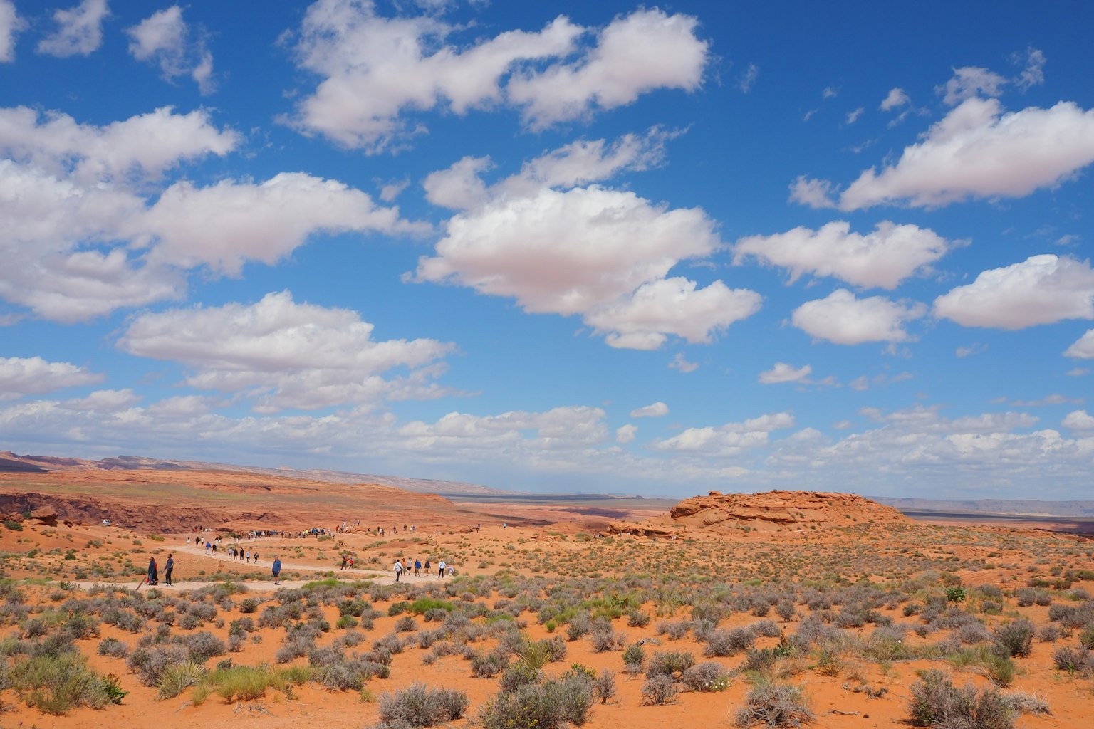 Paysage désertique rouge avec ciel bleu et nuages blancs duveteux