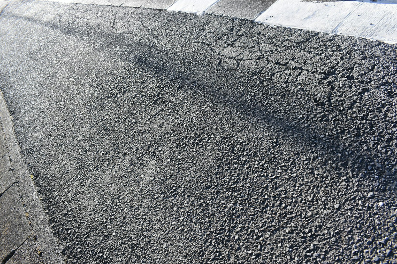 鋪砌道路的特寫圖像，顯示出裂紋的表面和陰影