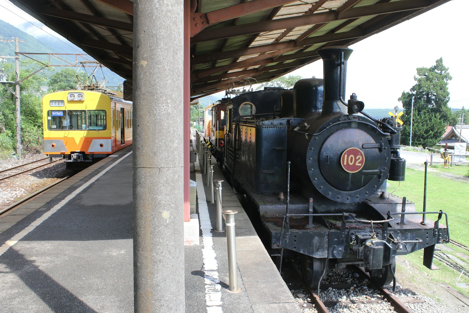 ภาพสถานีรถไฟที่มีรถจักรไอน้ำสีดำและรถไฟสีส้ม