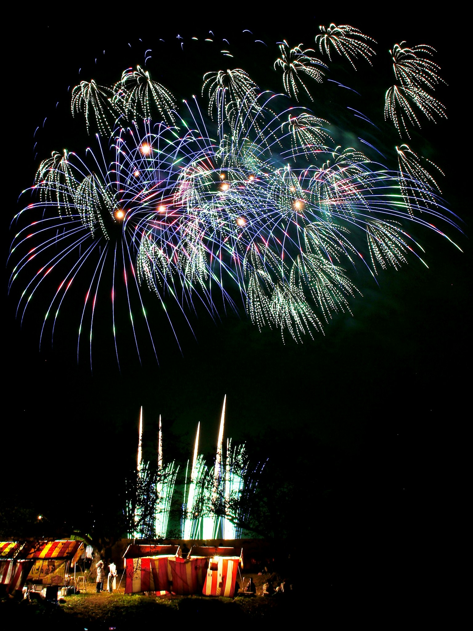Colorful fireworks lighting up the night sky above a festive fairground
