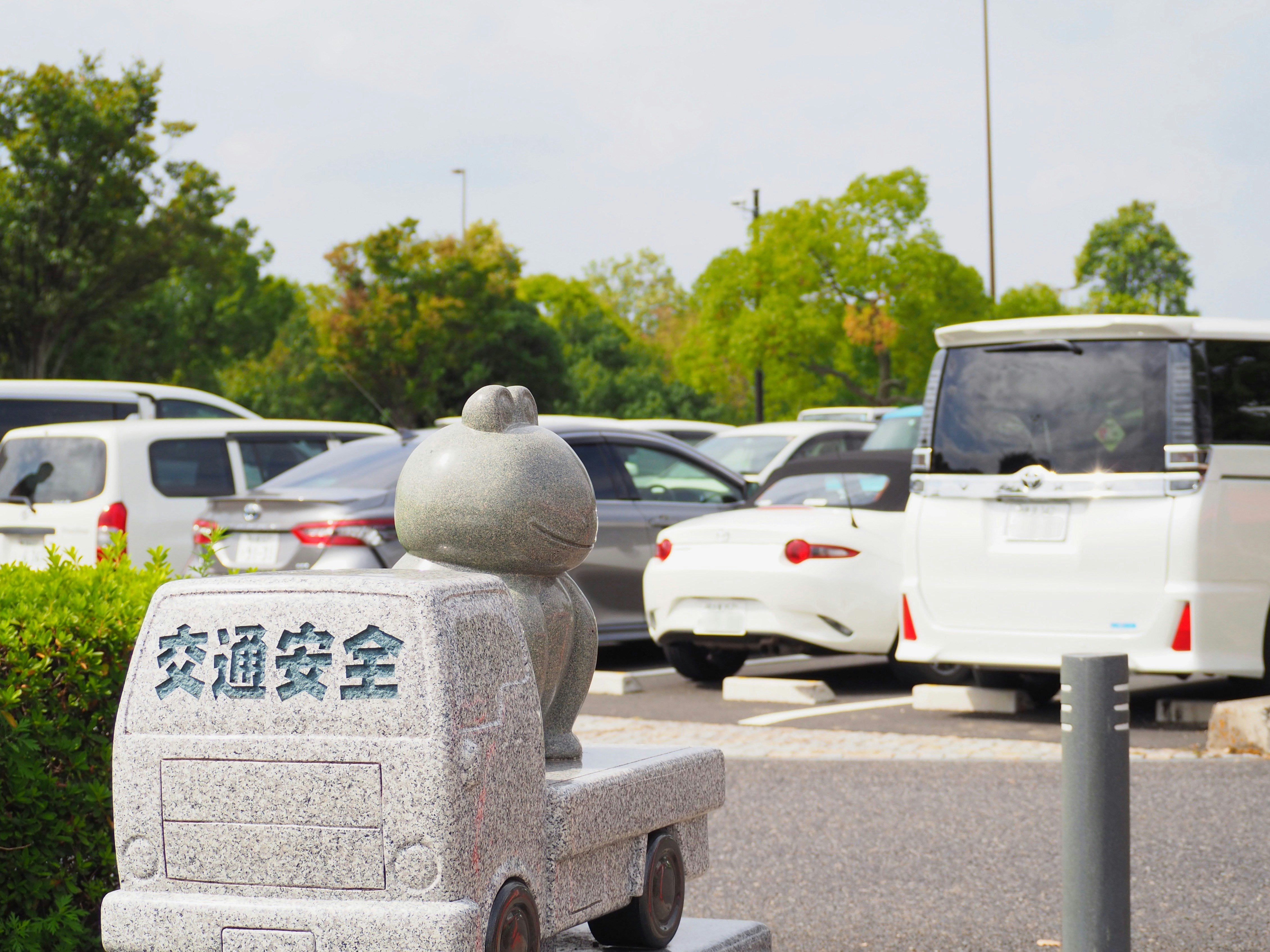 駐車場の交通安全の石像と車の列