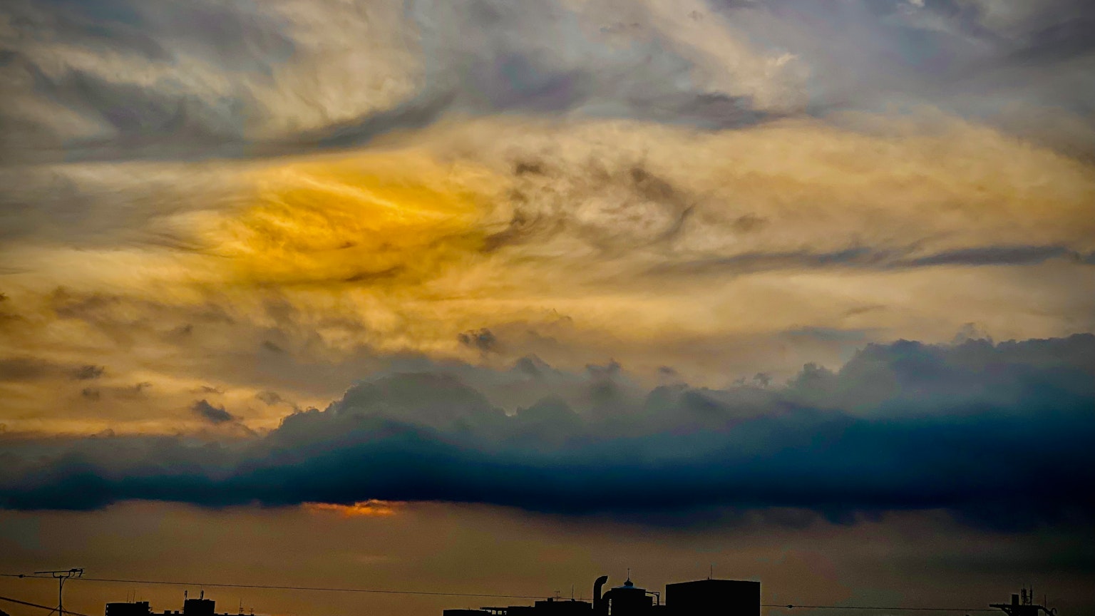 Siluet bangunan di latar belakang langit senja dramatis dengan awan