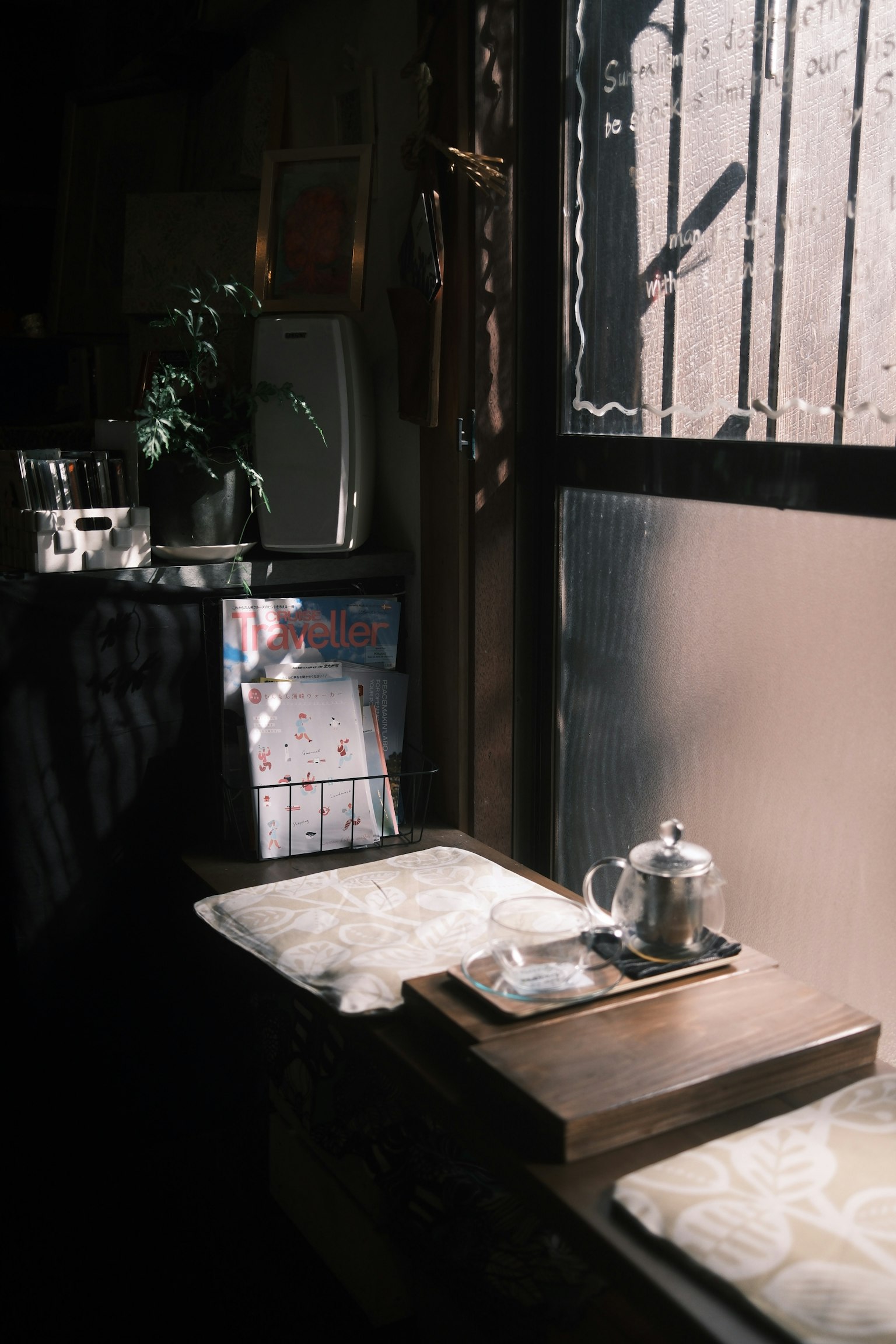 窓辺に置かれた銀色のティーポットと木製のトレイ 日差しが差し込む静かなカフェの一角