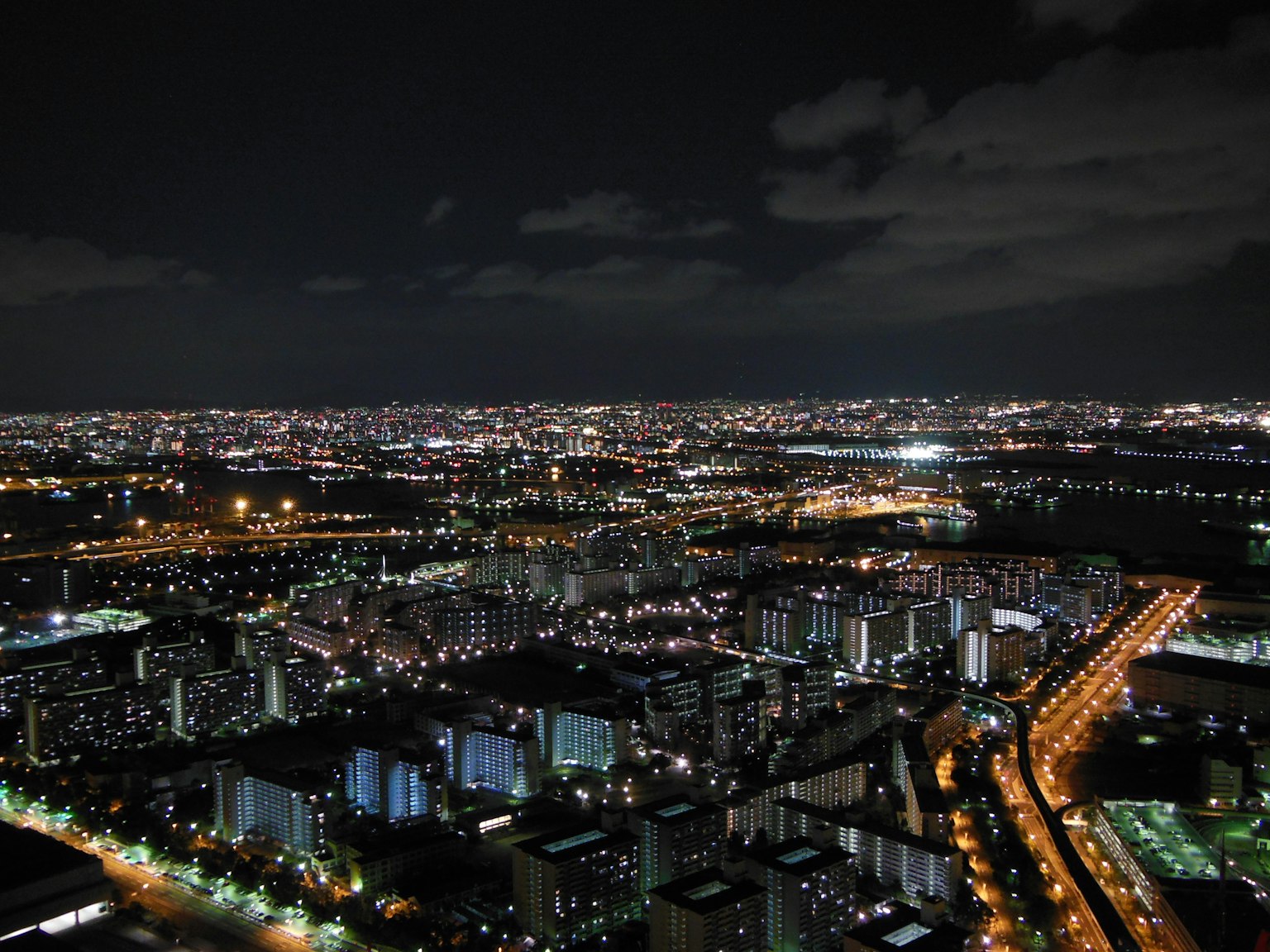 夜景城市天際線，燈光閃爍的建築和街道燈光，雲層覆蓋的天空