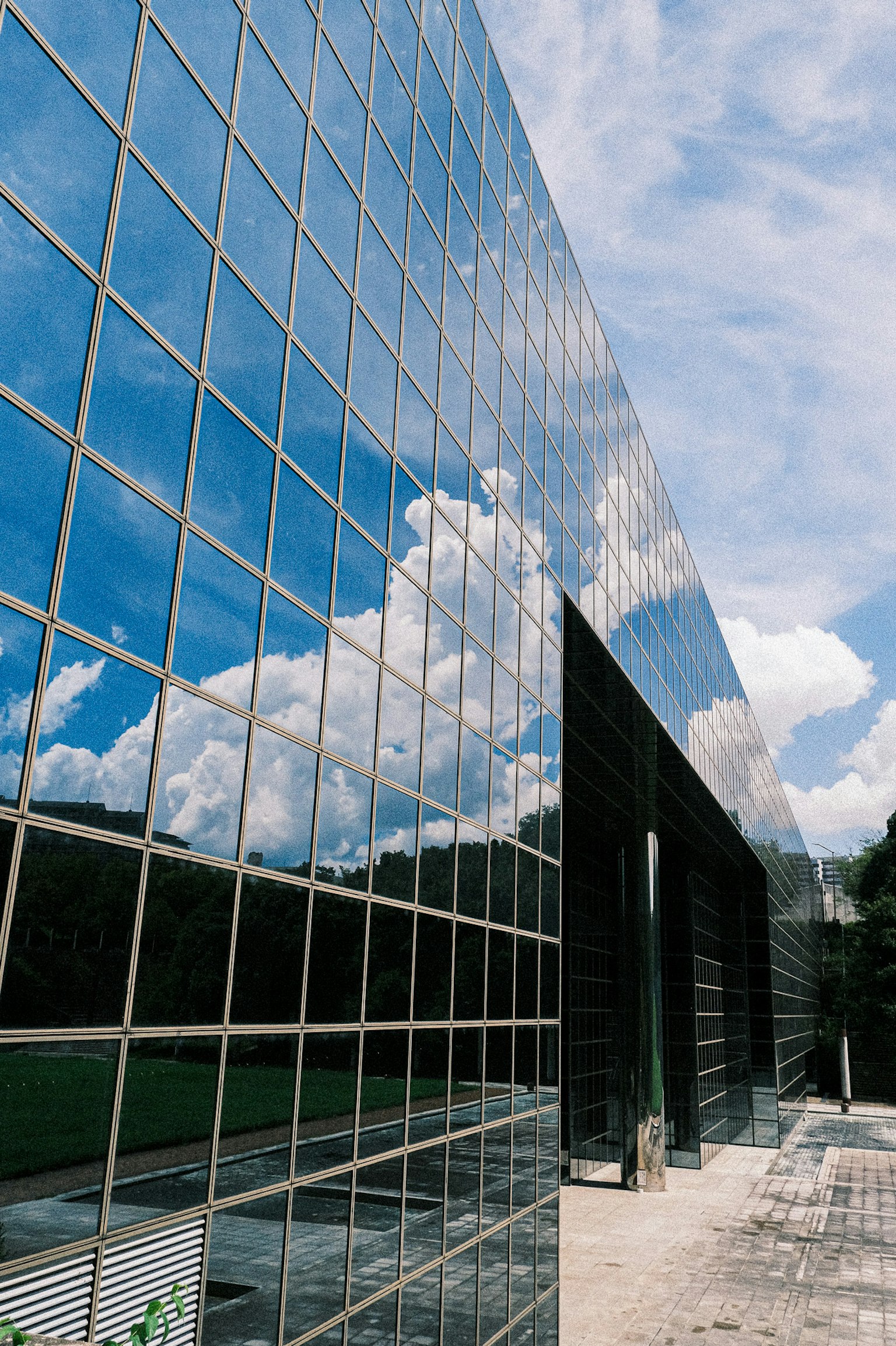 Glaswand, die den blauen Himmel und die Wolken in einem Winkel reflektiert
